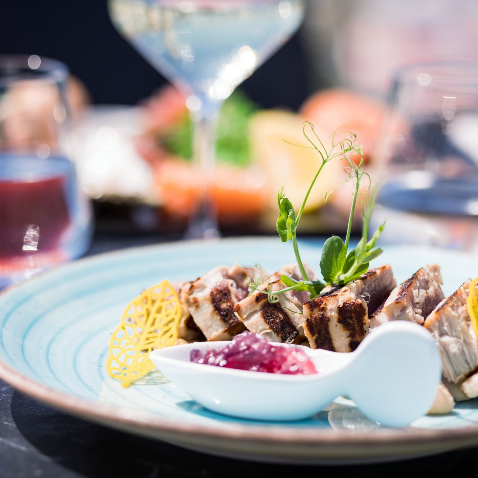 Un piatto di cibo con un cucchiaio e un bicchiere di vino sullo sfondo