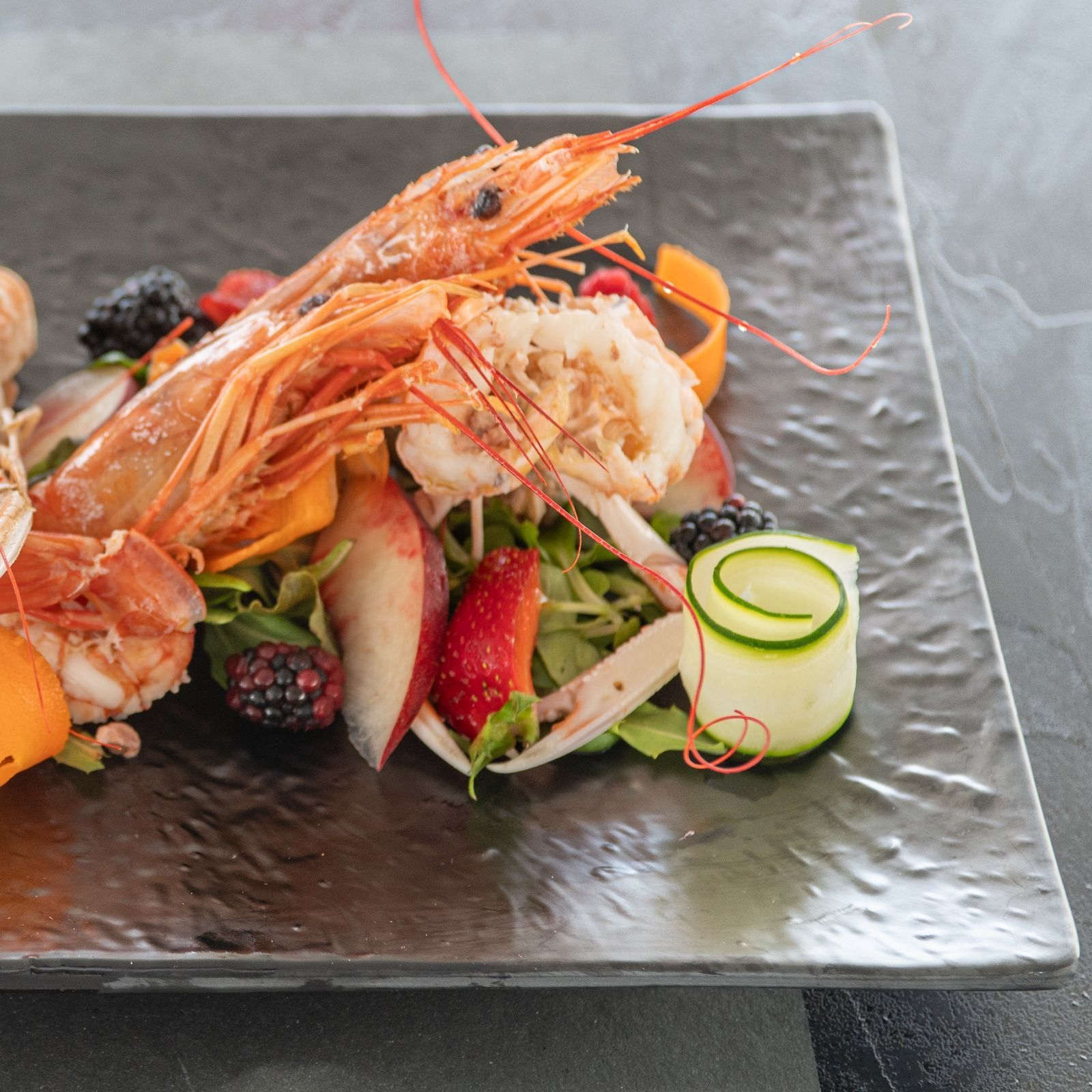 Un piatto di cibo con gamberi e frutta sopra