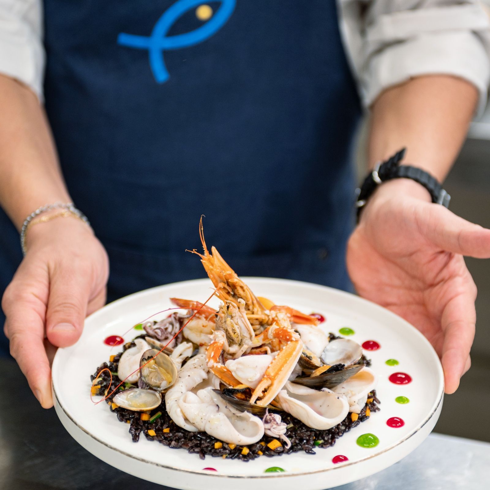Una persona con un grembiule tiene in mano un piatto di frutti di mare
