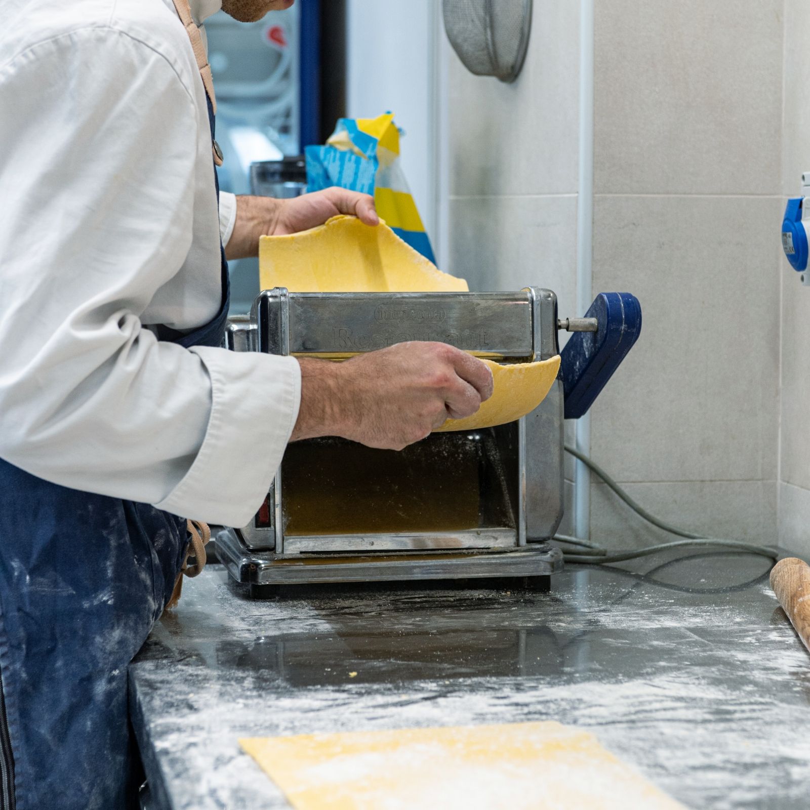 Un uomo sta usando una macchina per la pasta per fare la pasta