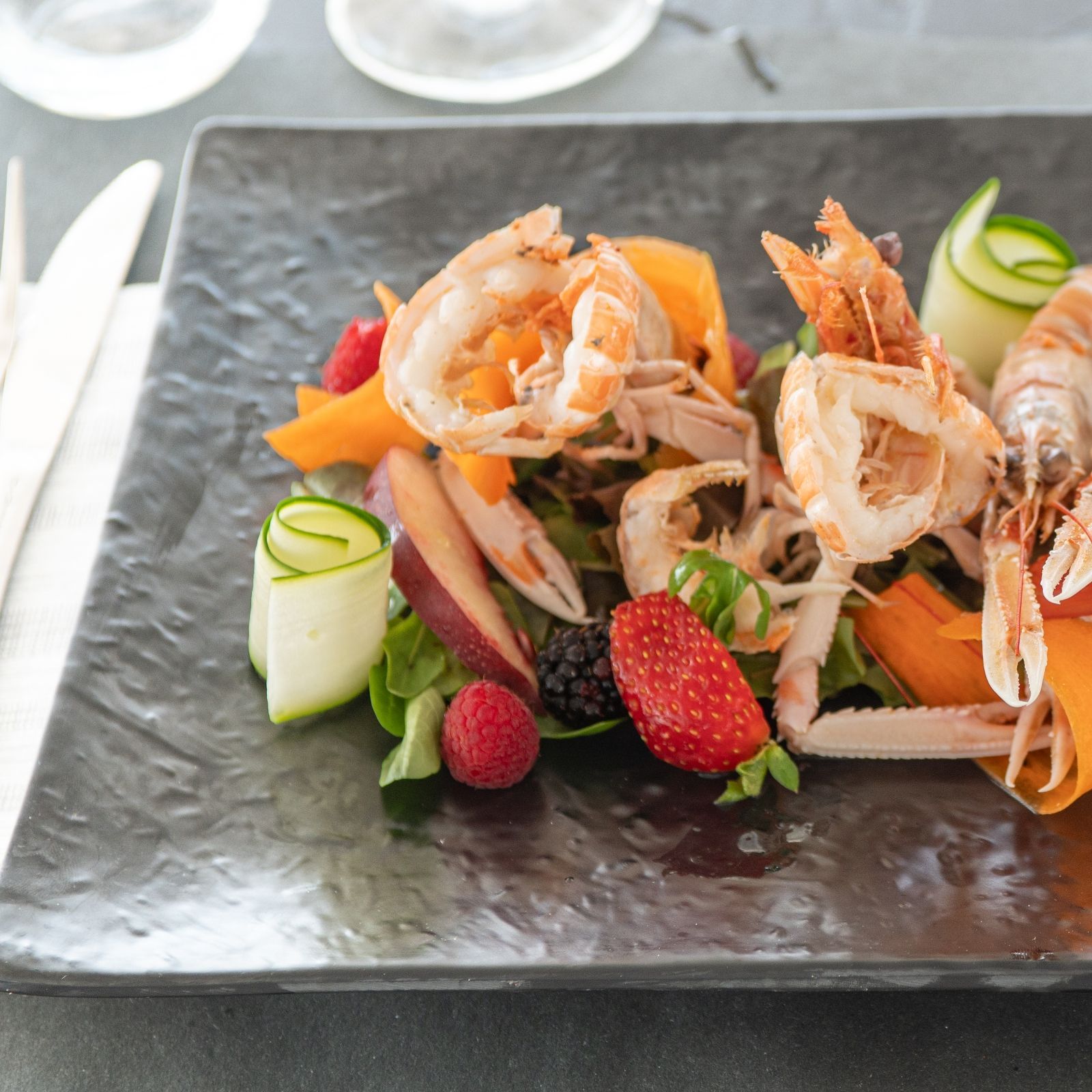 Un piatto di cibo con gamberi e fragole sopra