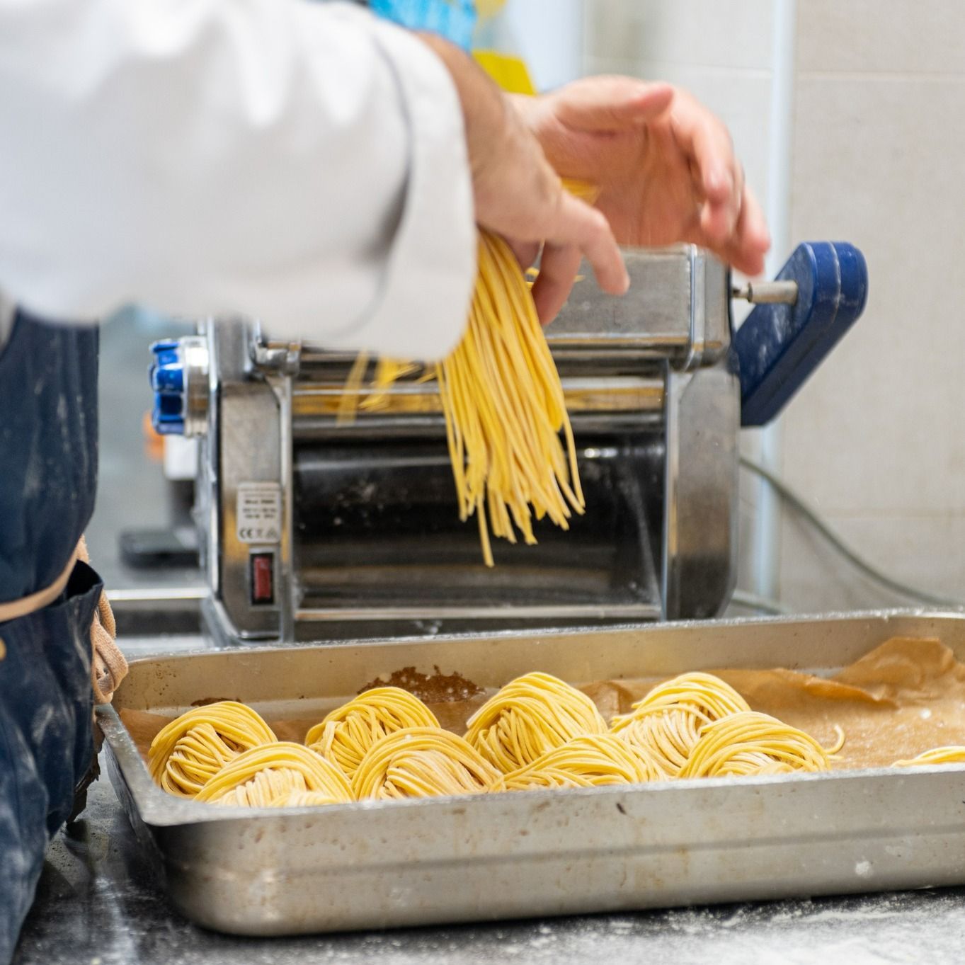 Una persona sta preparando le tagliatelle con una macchina.