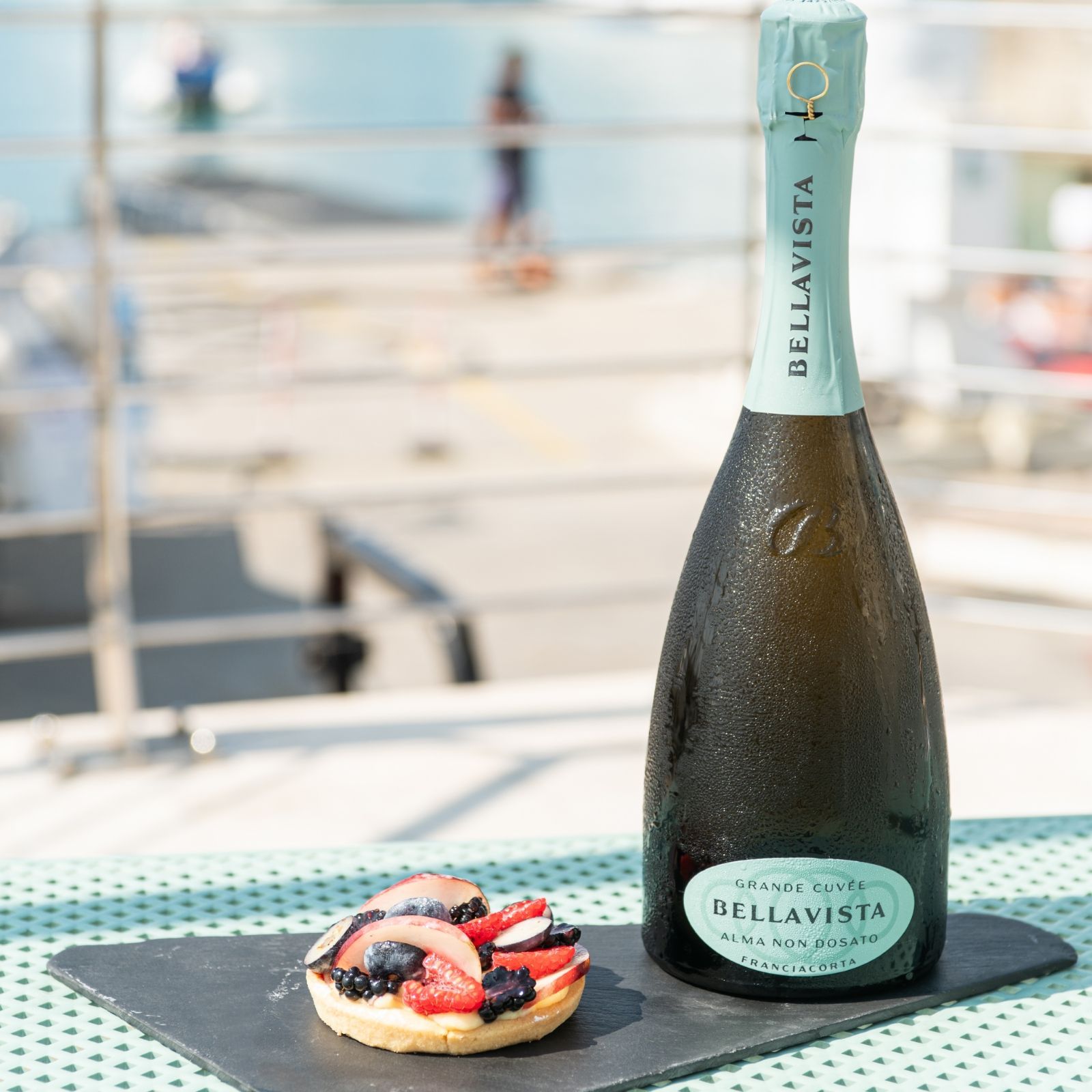 Una bottiglia di champagne Bellavista è appoggiata su un tavolo accanto a un dessert.