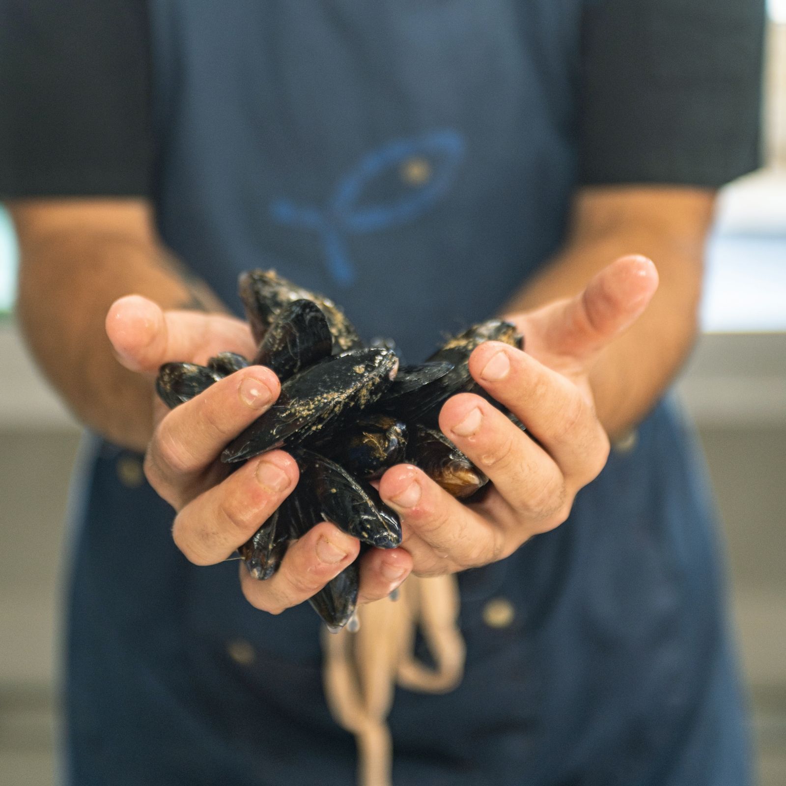 Un uomo tiene in mano un mazzo di cozze.