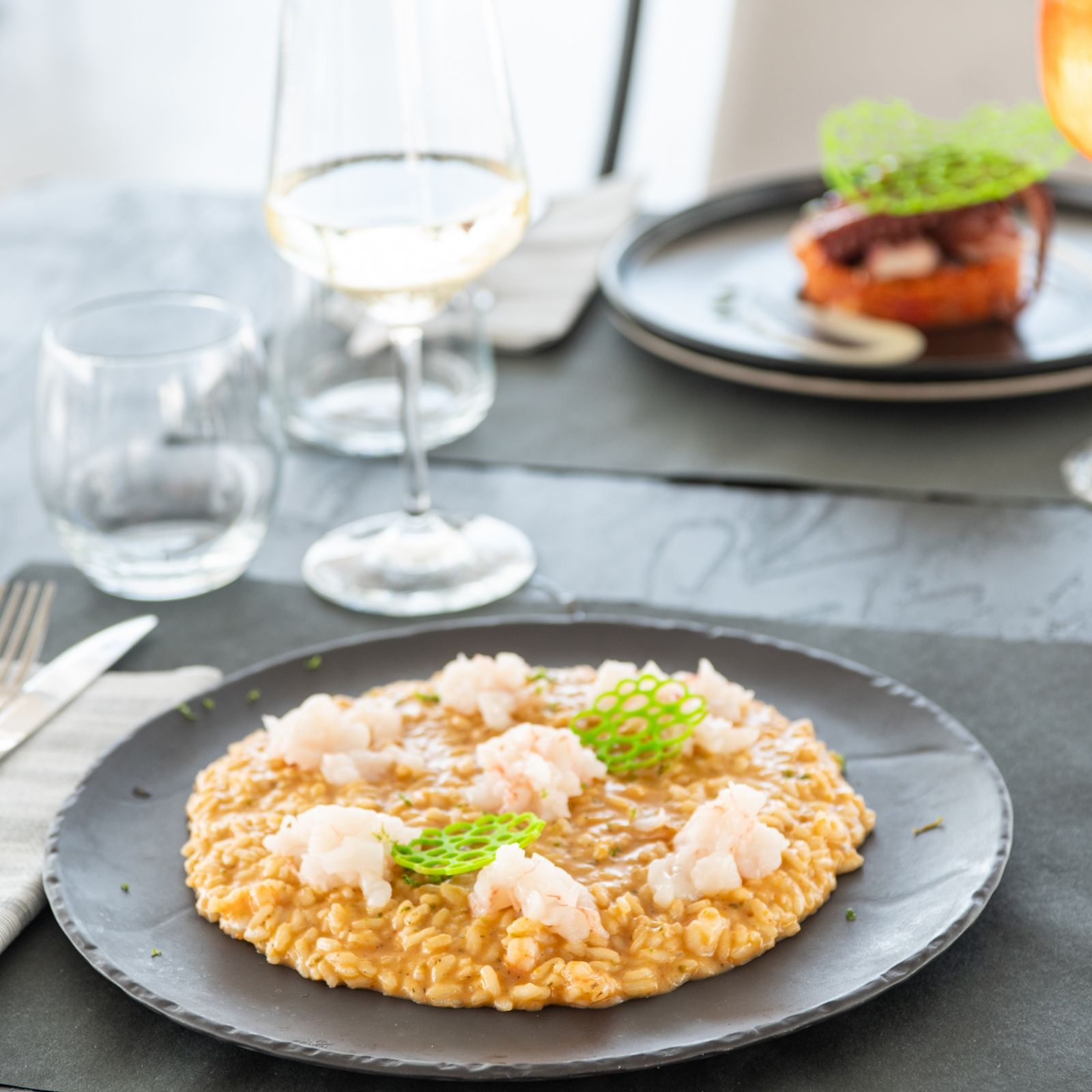 Un piatto di cibo su un tavolo con un bicchiere di vino sullo sfondo