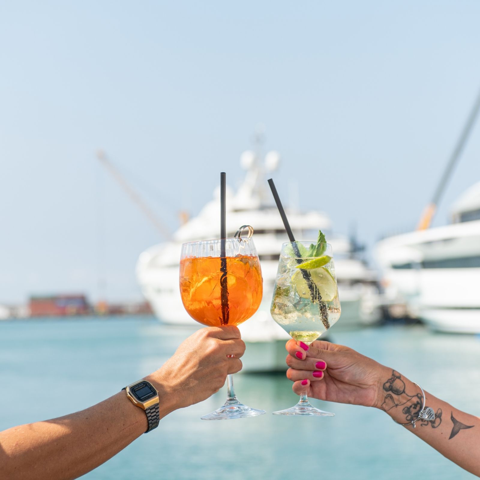 Un uomo e una donna stanno brindando con dei drink davanti a una barca.