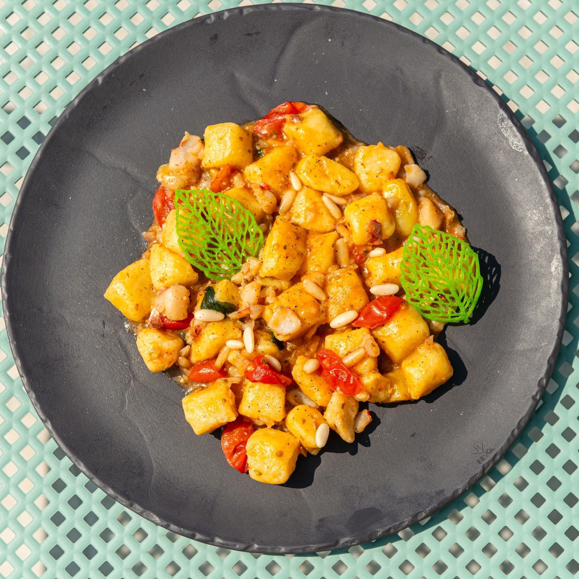 Un piatto nero con gnocchi e verdure su un tavolo