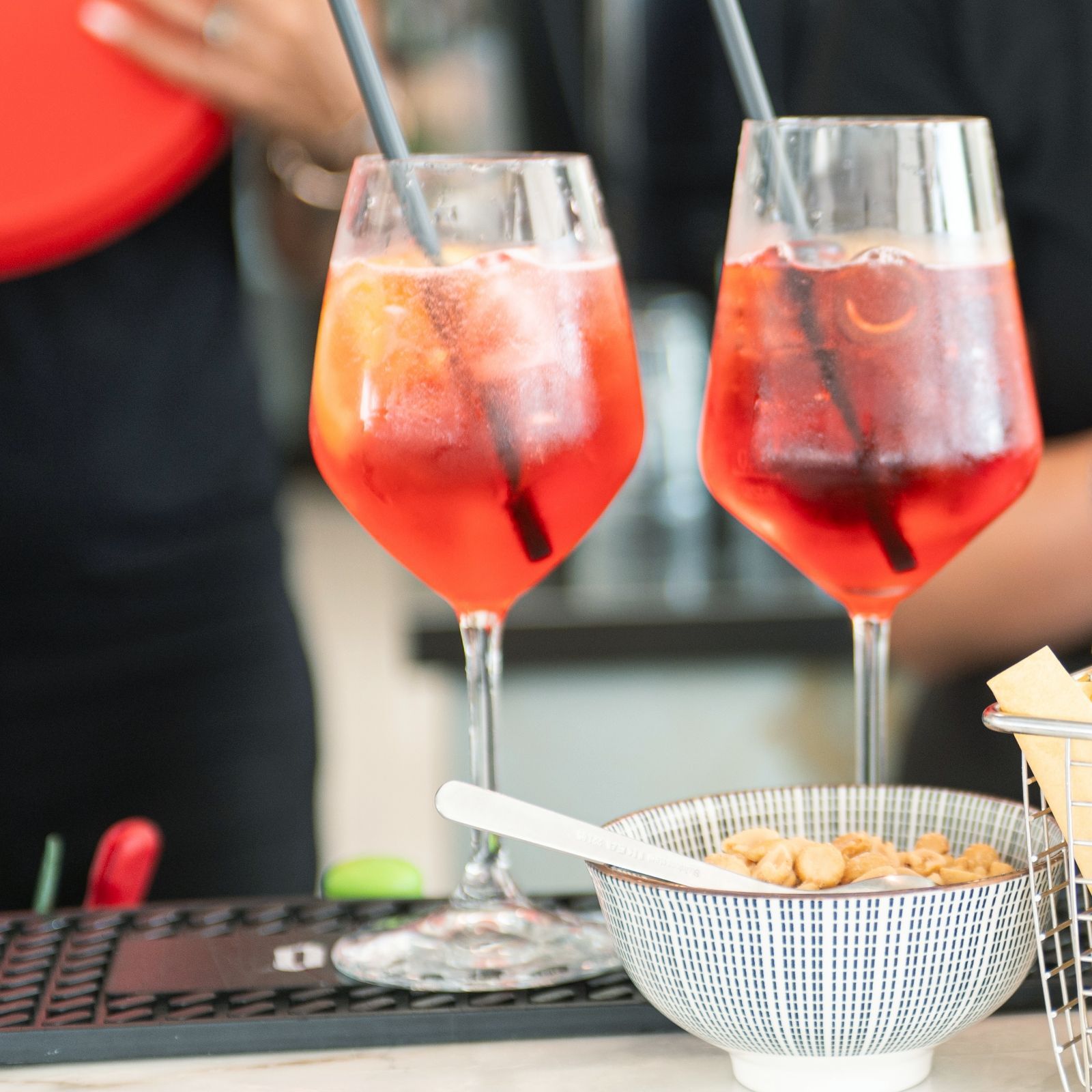 Due bicchieri di liquido rosso con cannucce e una ciotola di noci