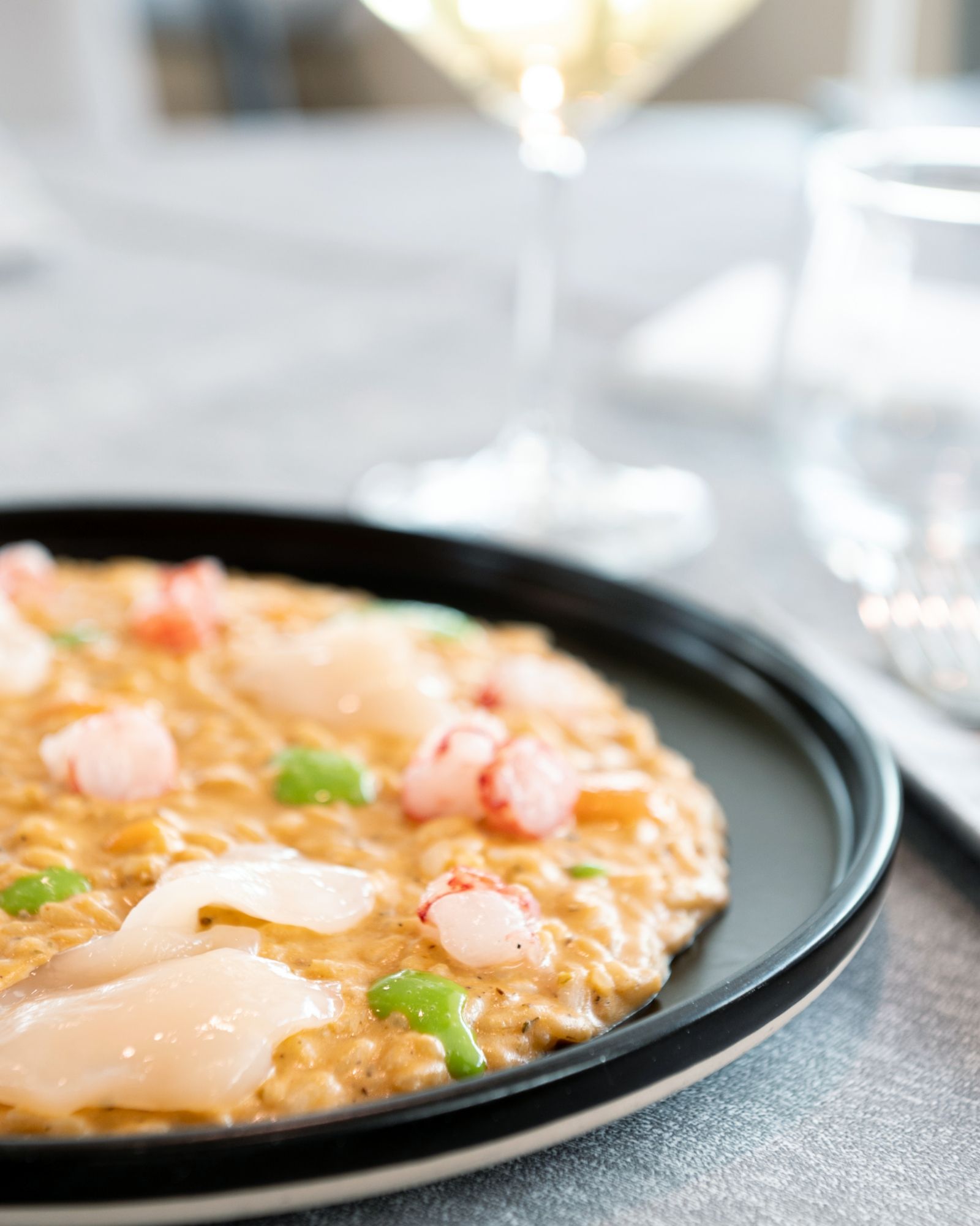 Un primo piano di un piatto di cibo con un bicchiere di vino sullo sfondo.