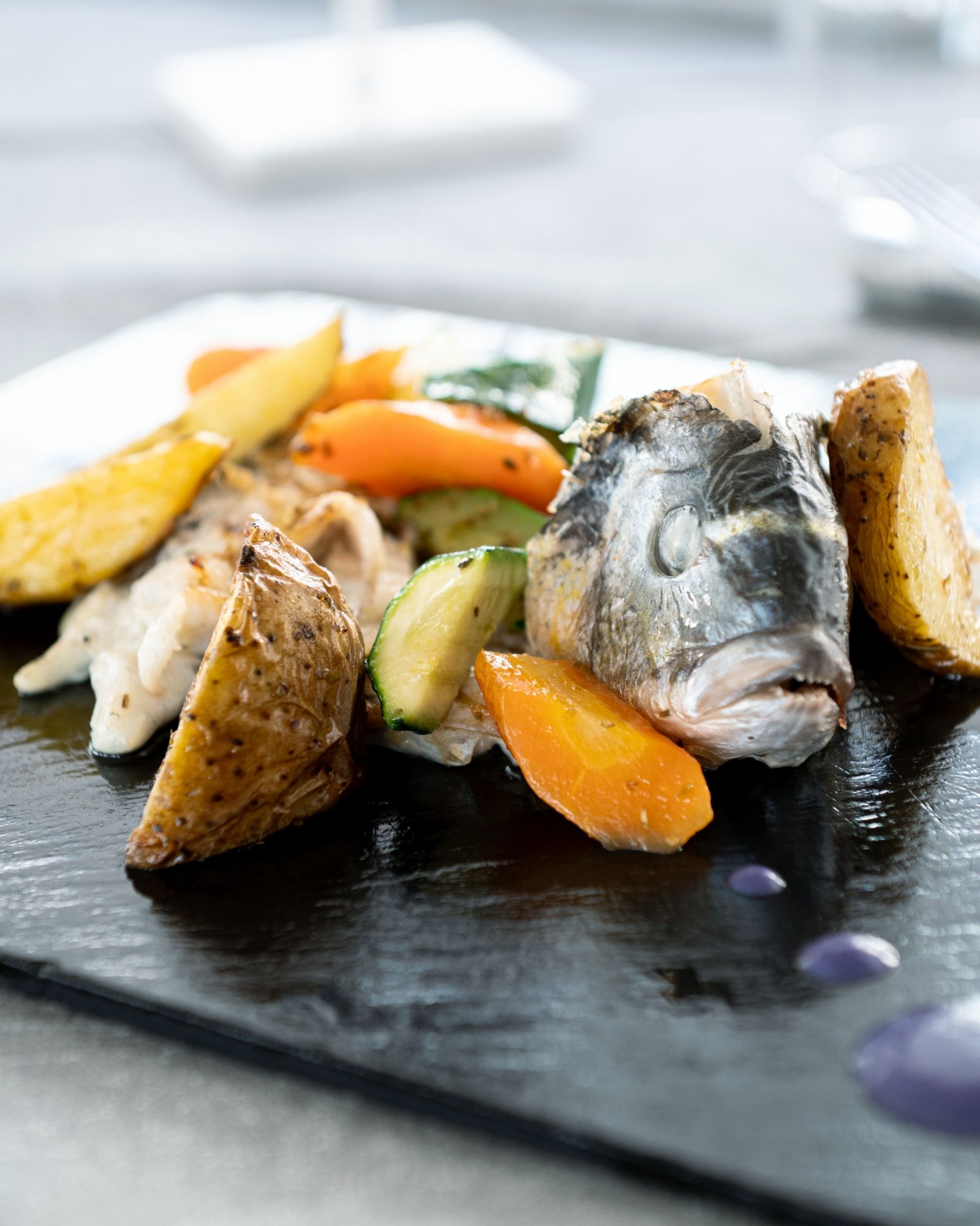 Primo piano di un piatto di cibo con pesce e verdure su un tavolo.