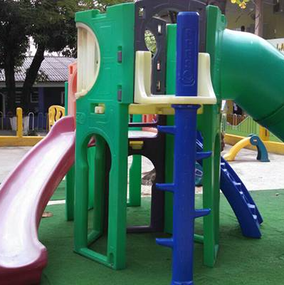 Um playground verde com um escorregador azul e um escorregador roxo