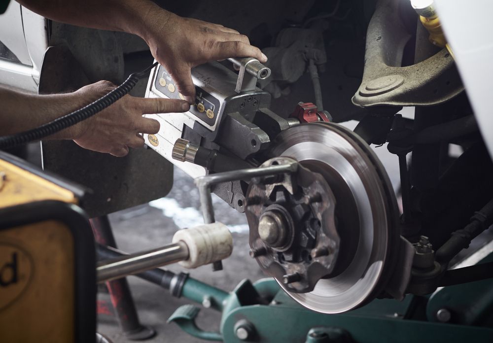 A Man Is Working On A Brake Disc On A Car — Bakers Creek Wreckers In Bakers Creek, QLD