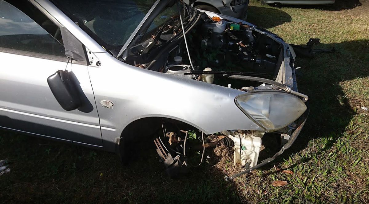 A Silver Car with The Hood Open Is Sitting in The Grass — Bakers Creek Wreckers In Bakers Creek, QLD