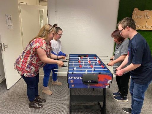 a group of people are playing foosball in a room .