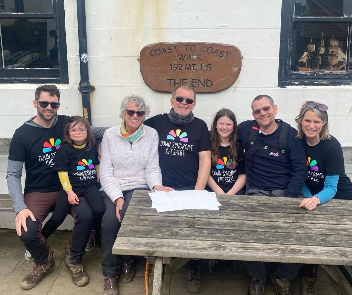 A group of people are posing for a picture in front of a sign that says coast to coast