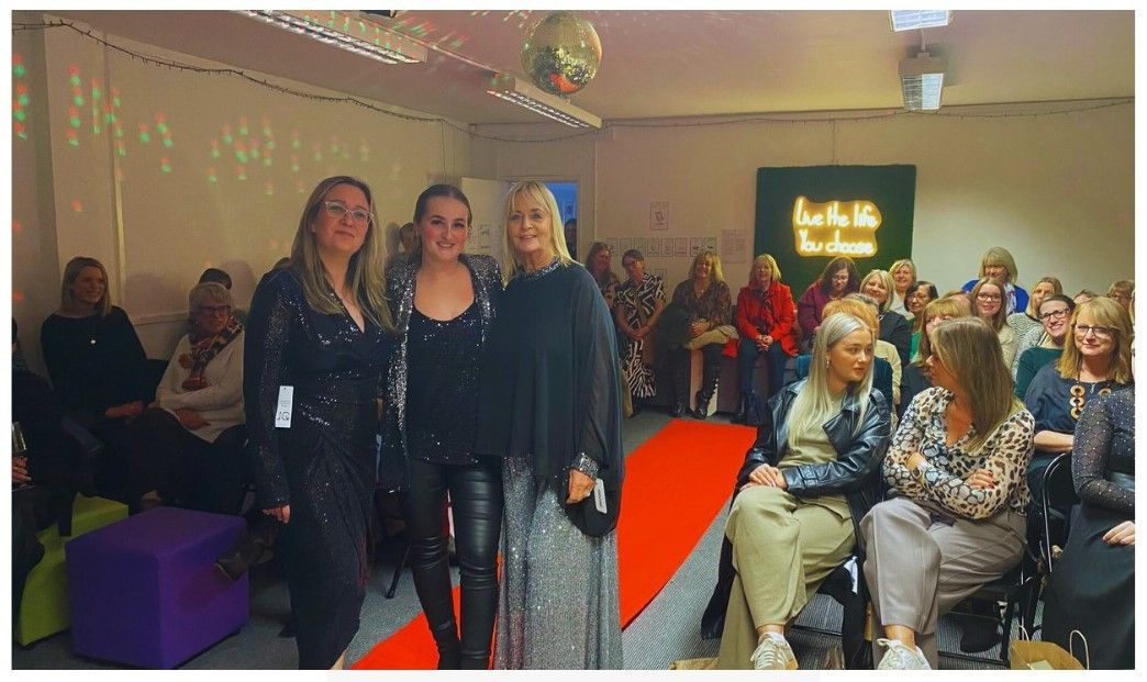 Three women facing the camera at a Down Syndrome Cheshire fashion fundraising event.