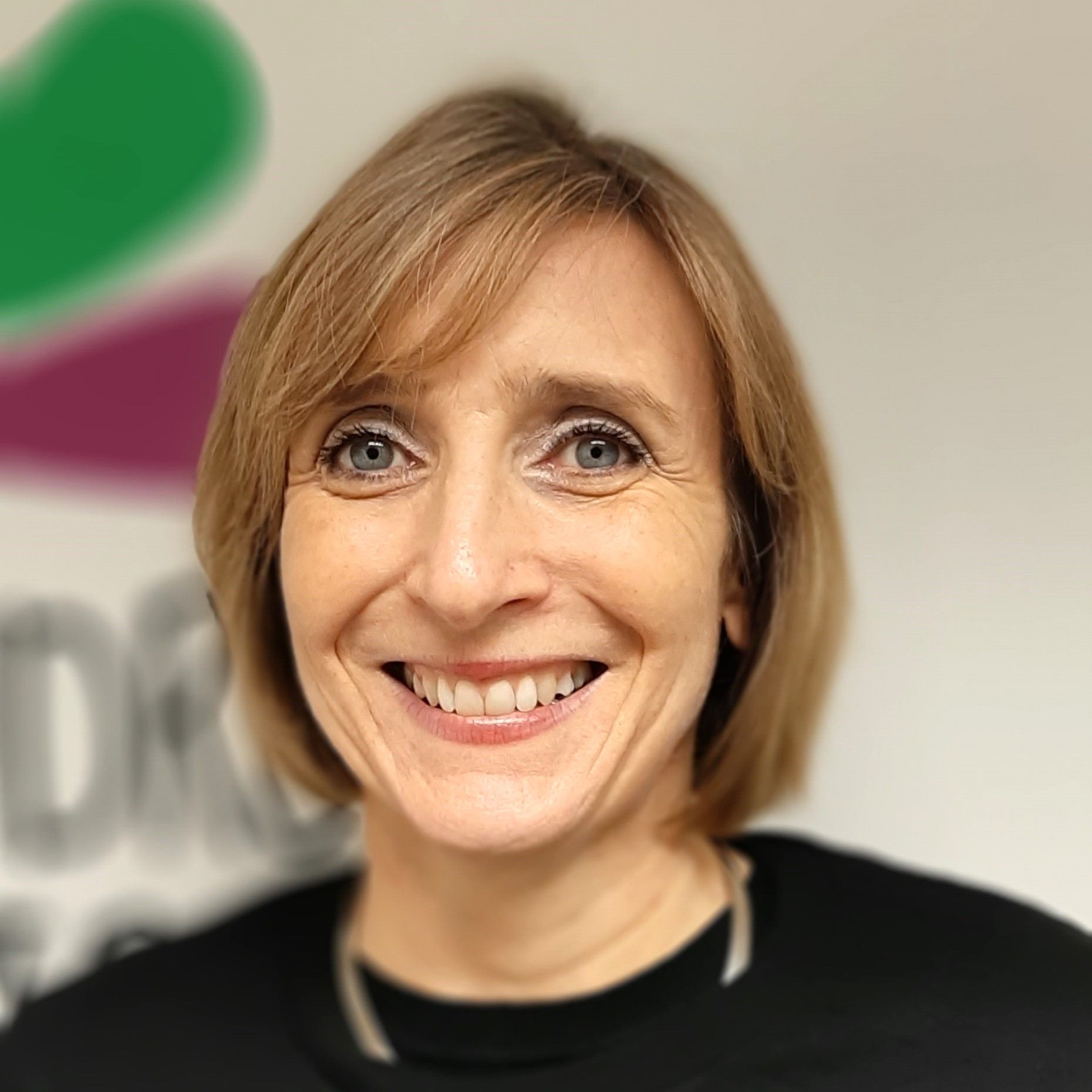 a woman is smiling for the camera and wearing a black shirt .