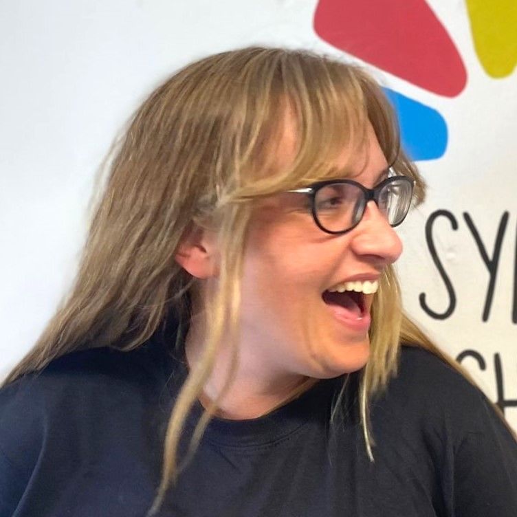 a woman wearing glasses is laughing with her mouth open