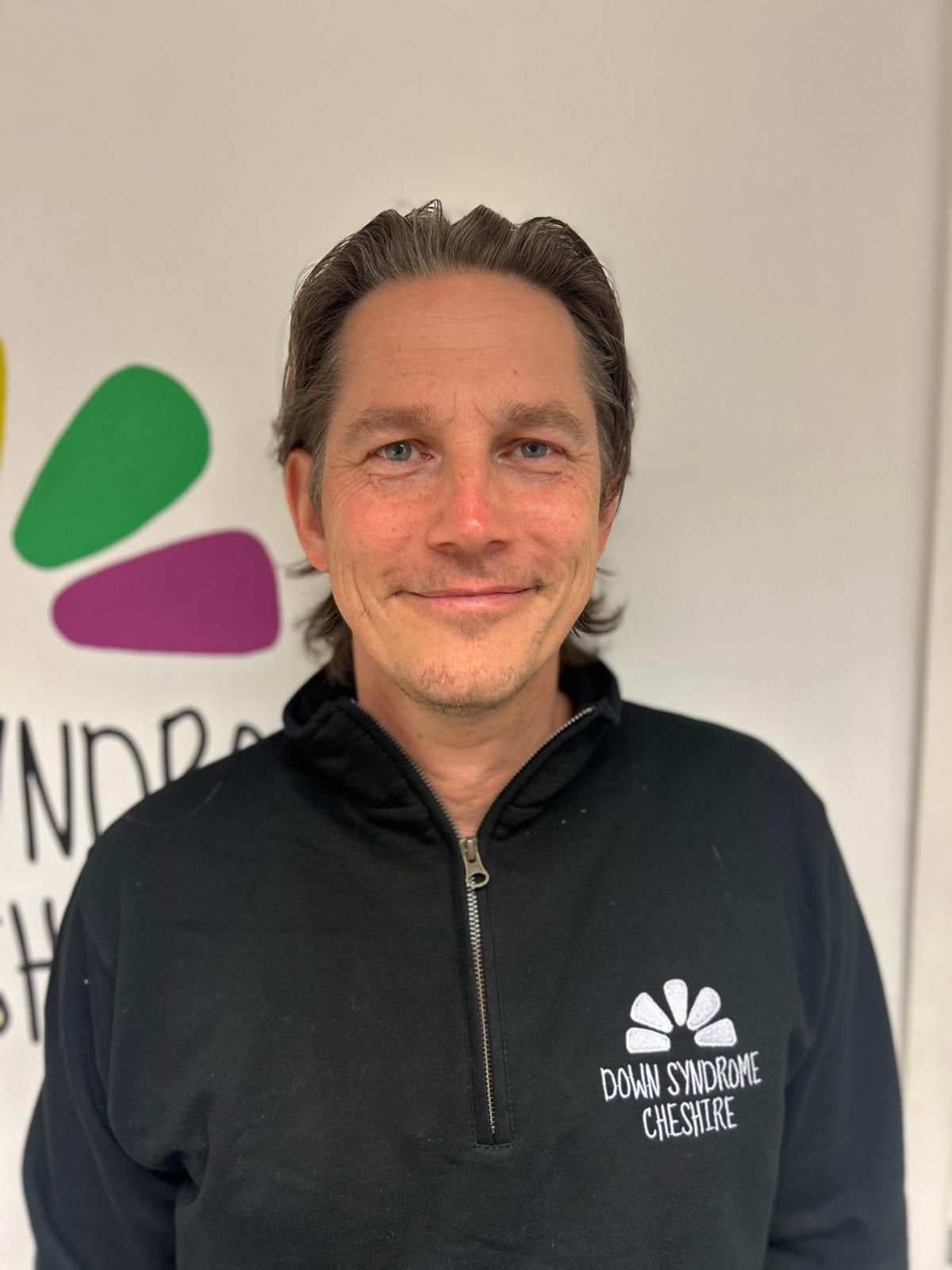 a man wearing a black hoodie is smiling for the camera