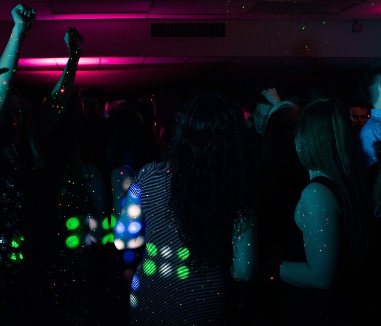 a group of people are dancing in a dark room at a party .