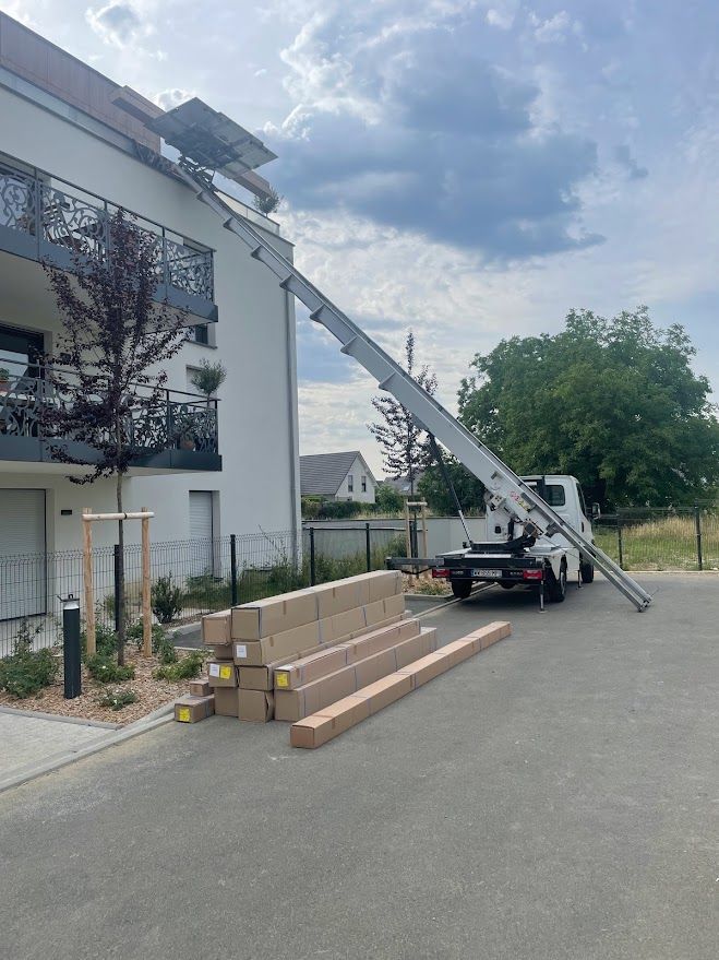 Un camion avec une échelle attachée est garé devant un bâtiment.