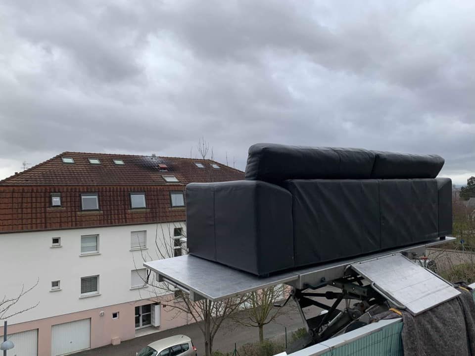 Un canapé noir est posé sur une plate-forme en métal.