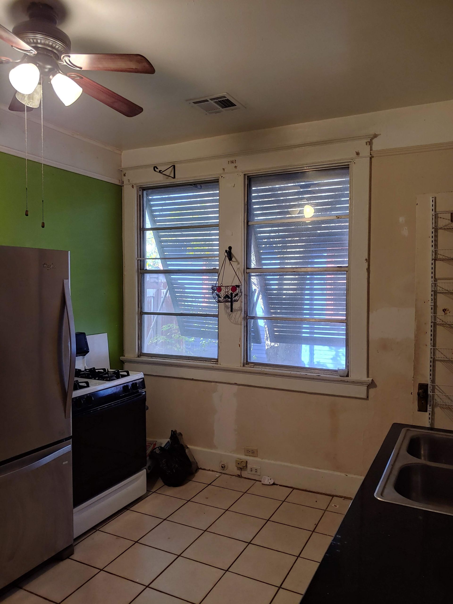 A kitchen with a ceiling fan and two windows