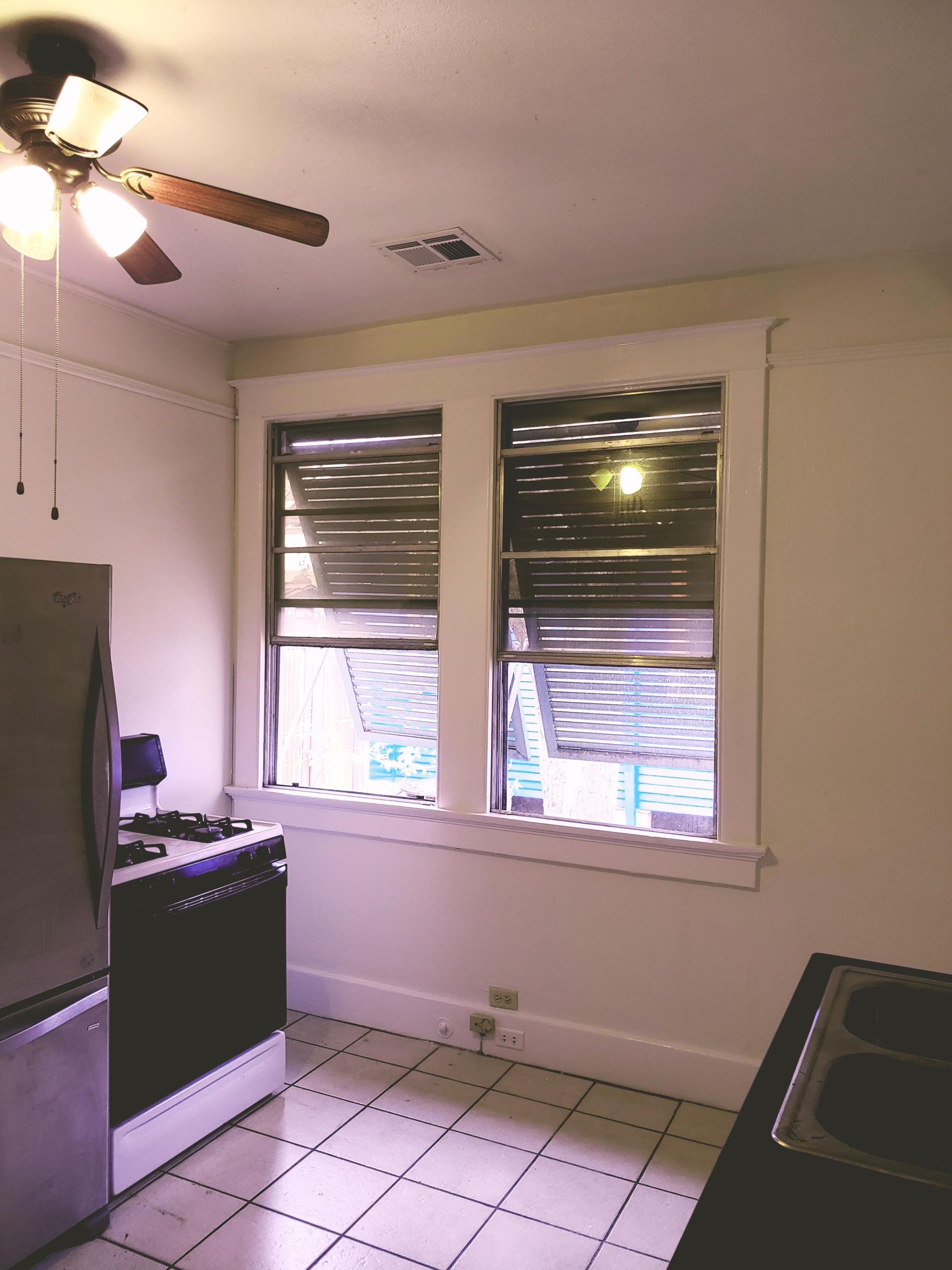 A kitchen with two windows and a ceiling fan