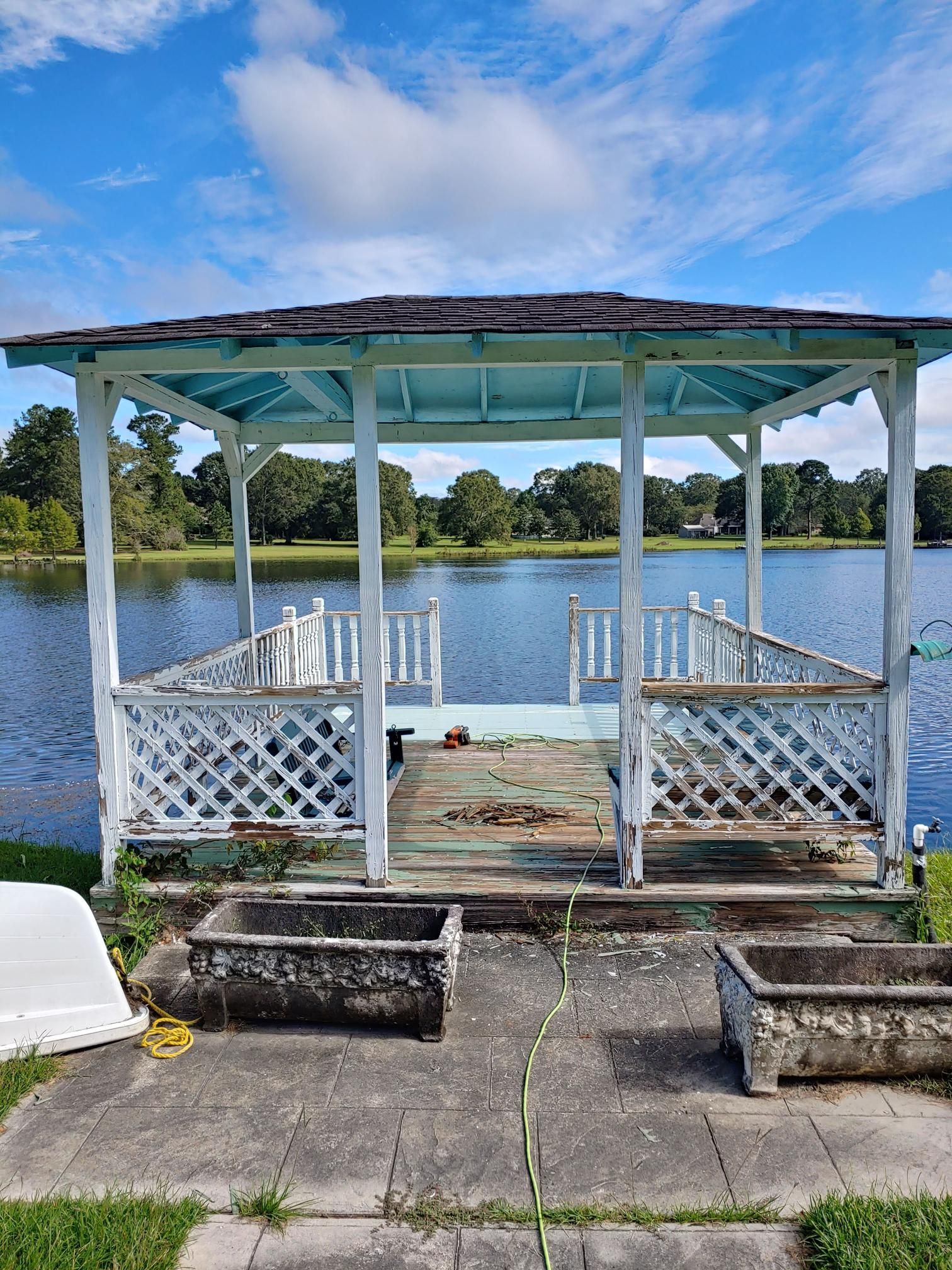 A gazebo is sitting on the shore of a lake.