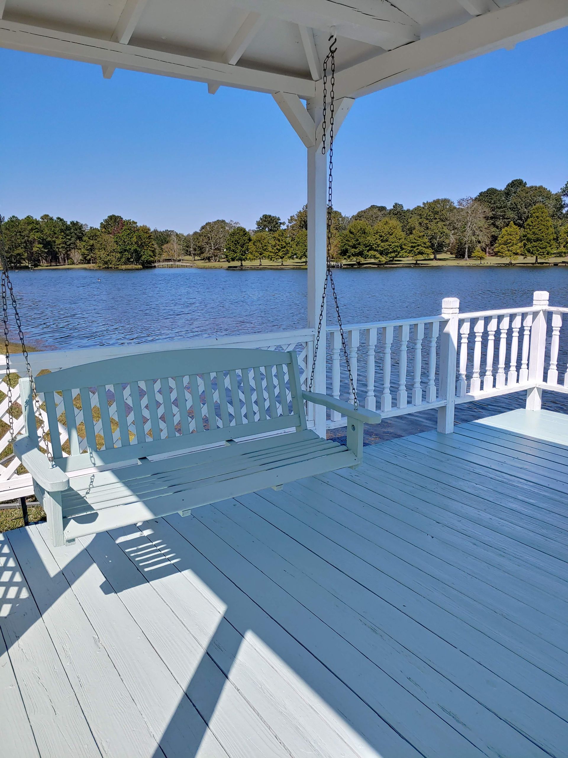 A porch with a swing overlooking a lake