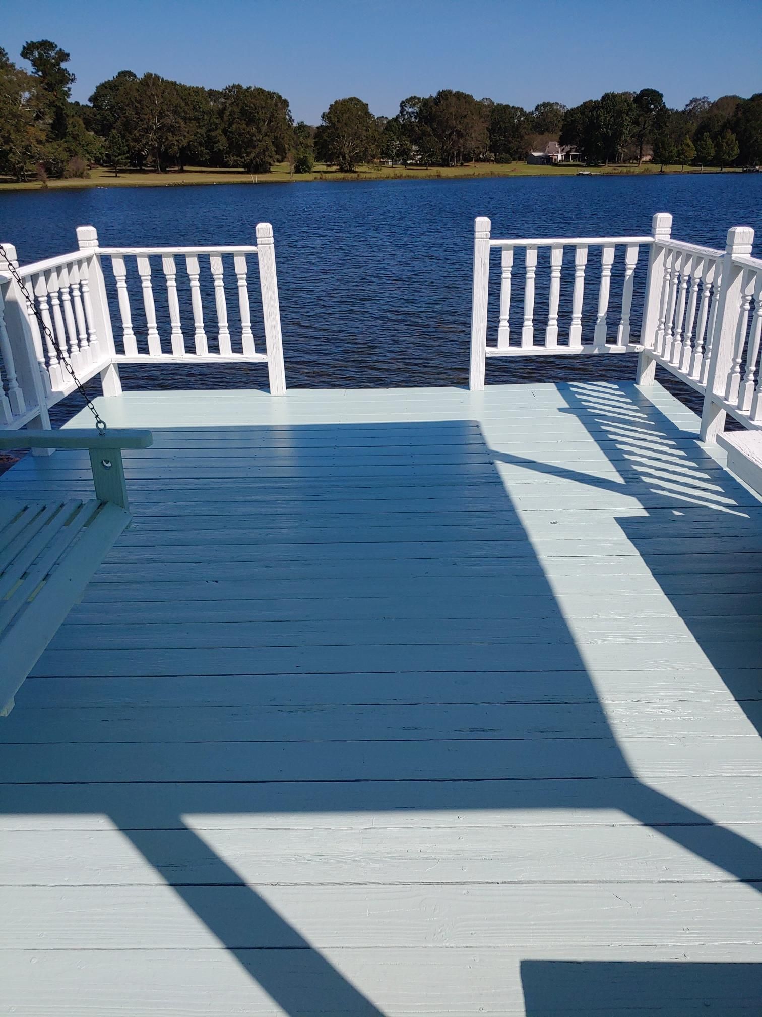 A blue deck with white railings overlooking a lake.