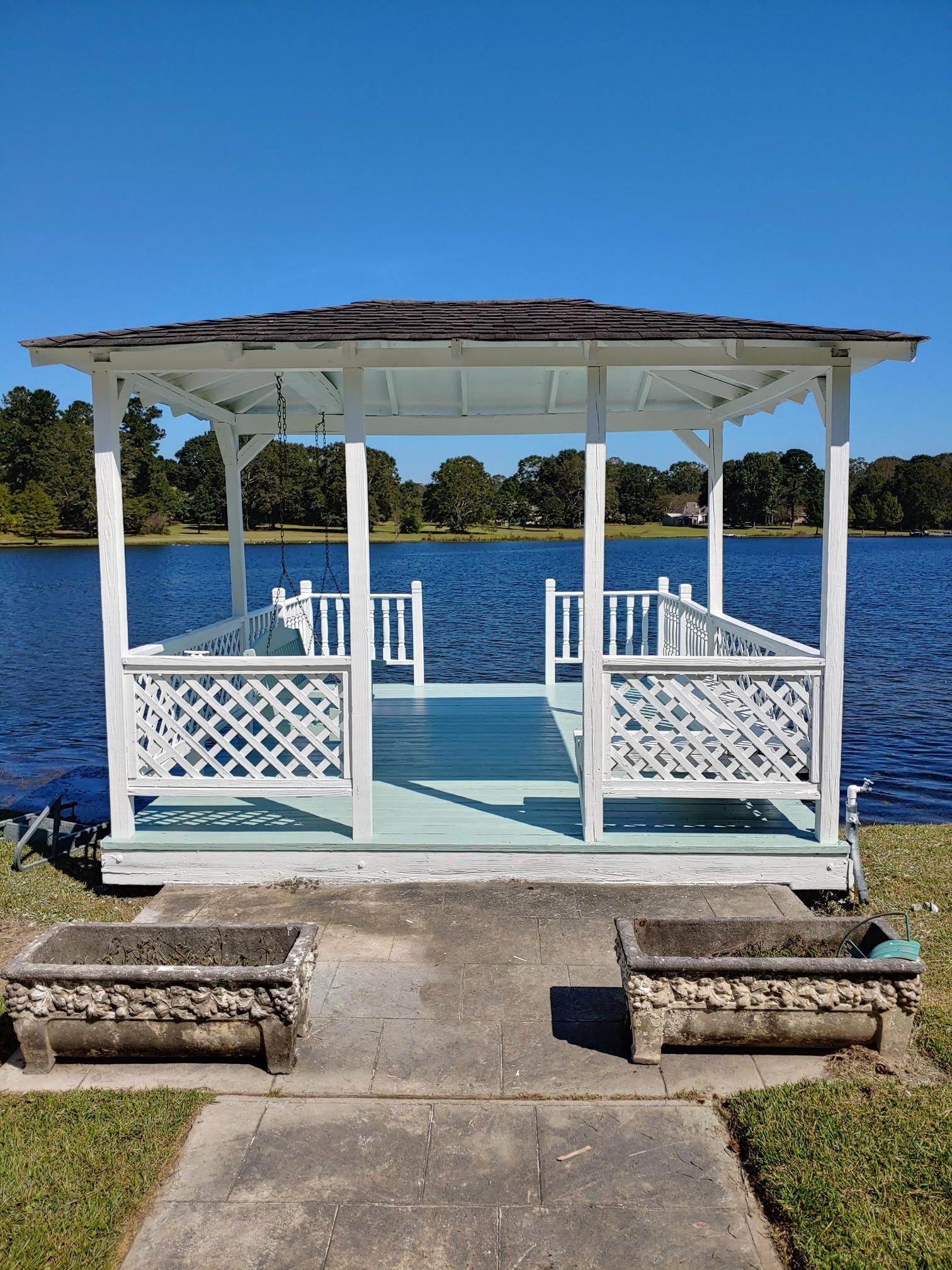 A white gazebo is sitting on the shore of a lake.