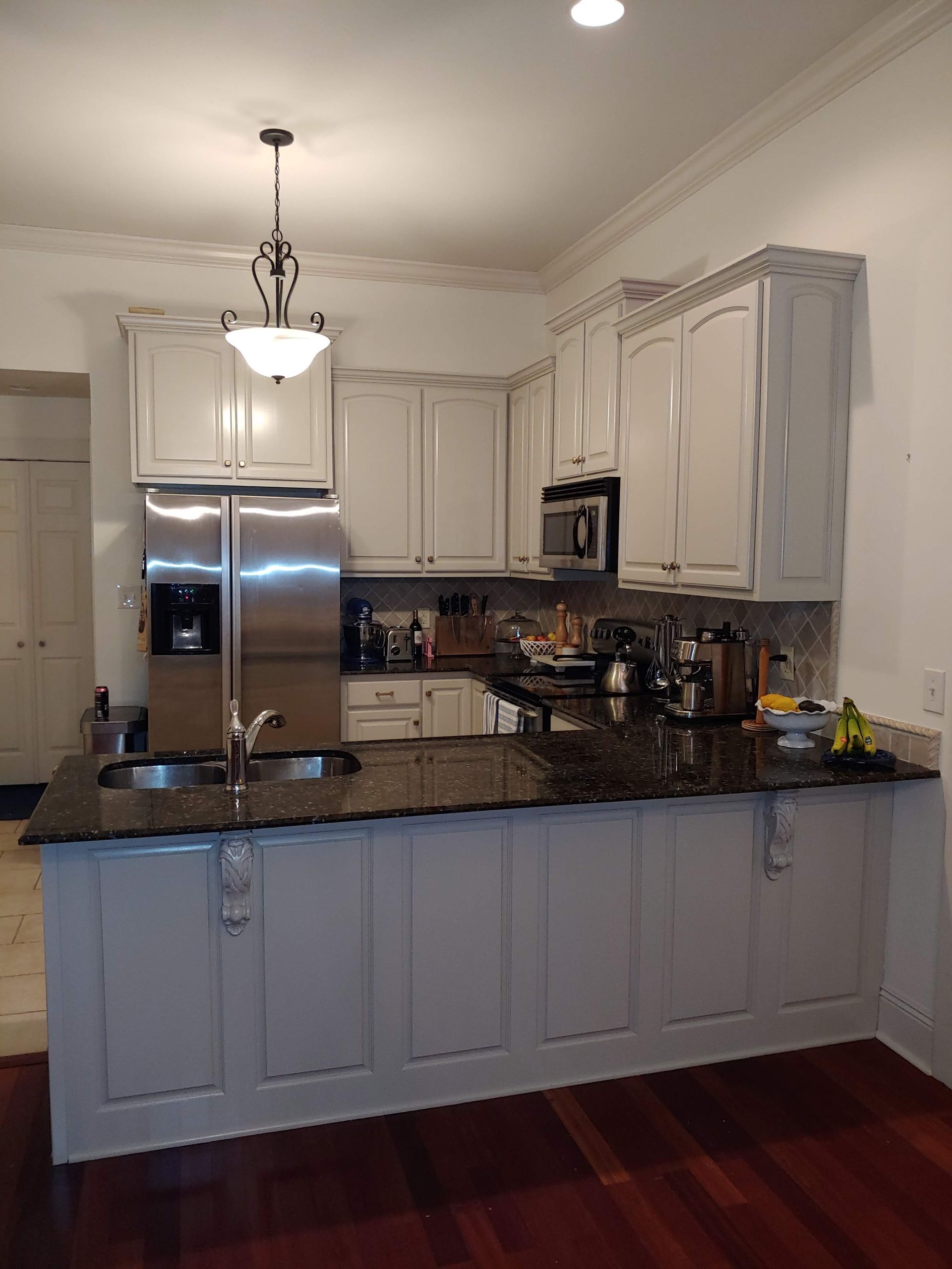 A kitchen with white cabinets , granite counter tops , stainless steel appliances and a large island.