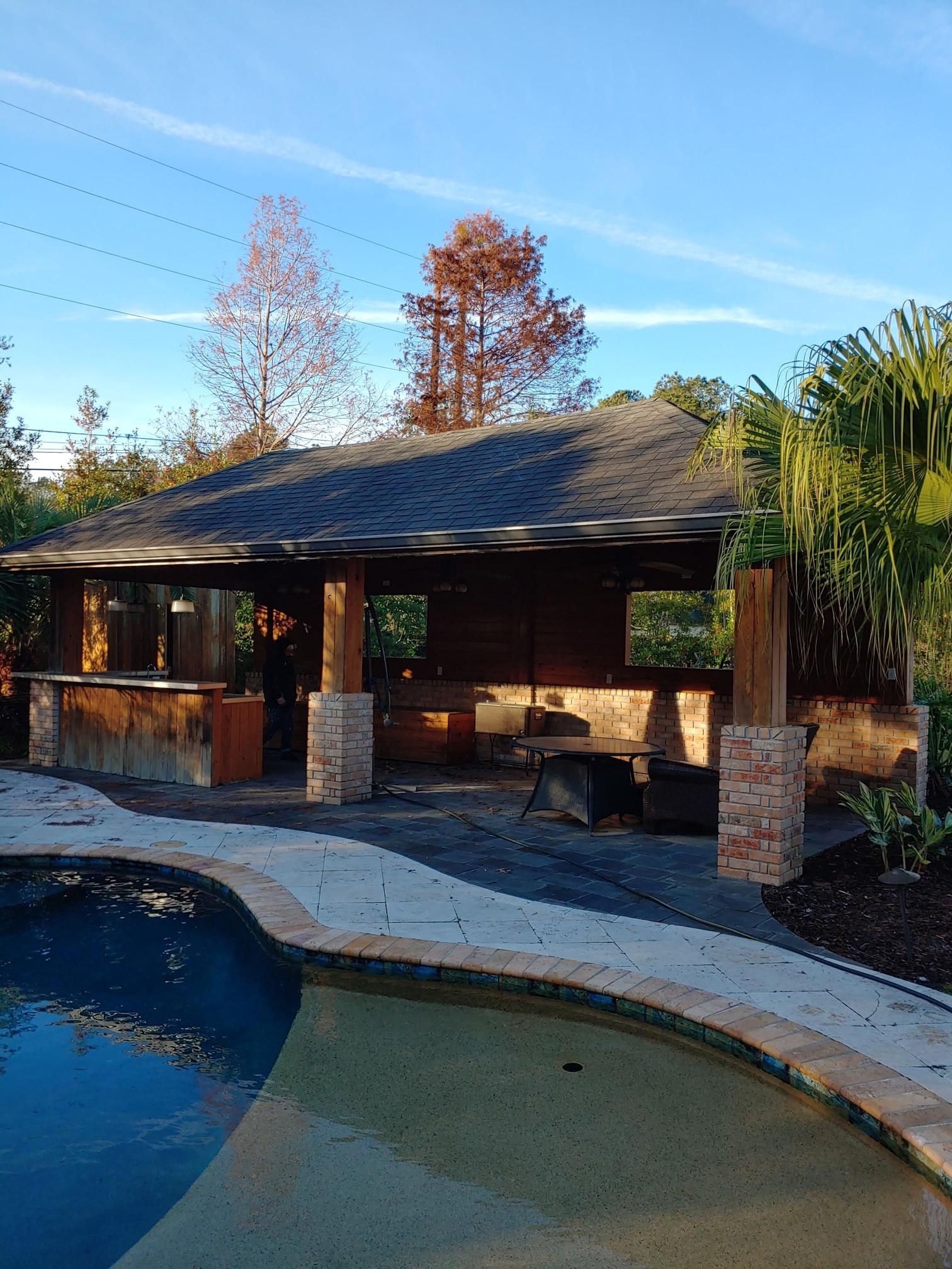 A pool with a pavilion in the background and trees in the background