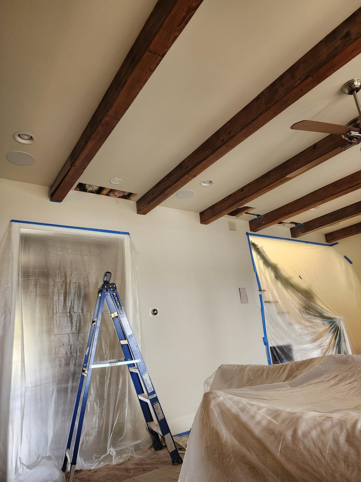 A room with a ladder and a ceiling fan in it