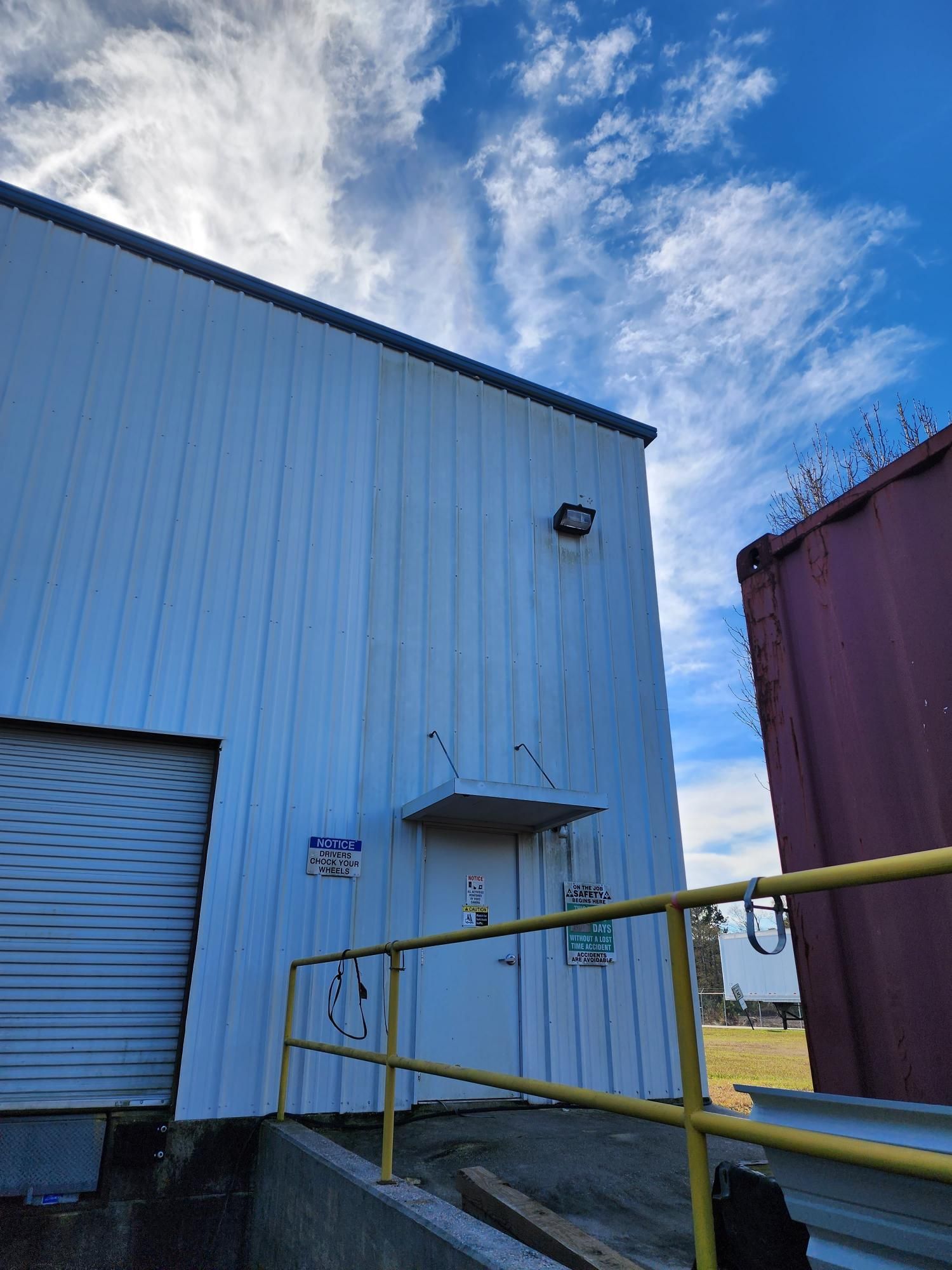 A white building with a yellow railing and a door.