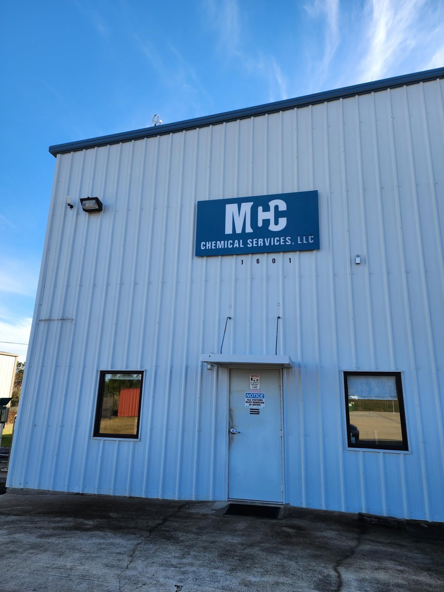 A white building with a blue sign that says mhc