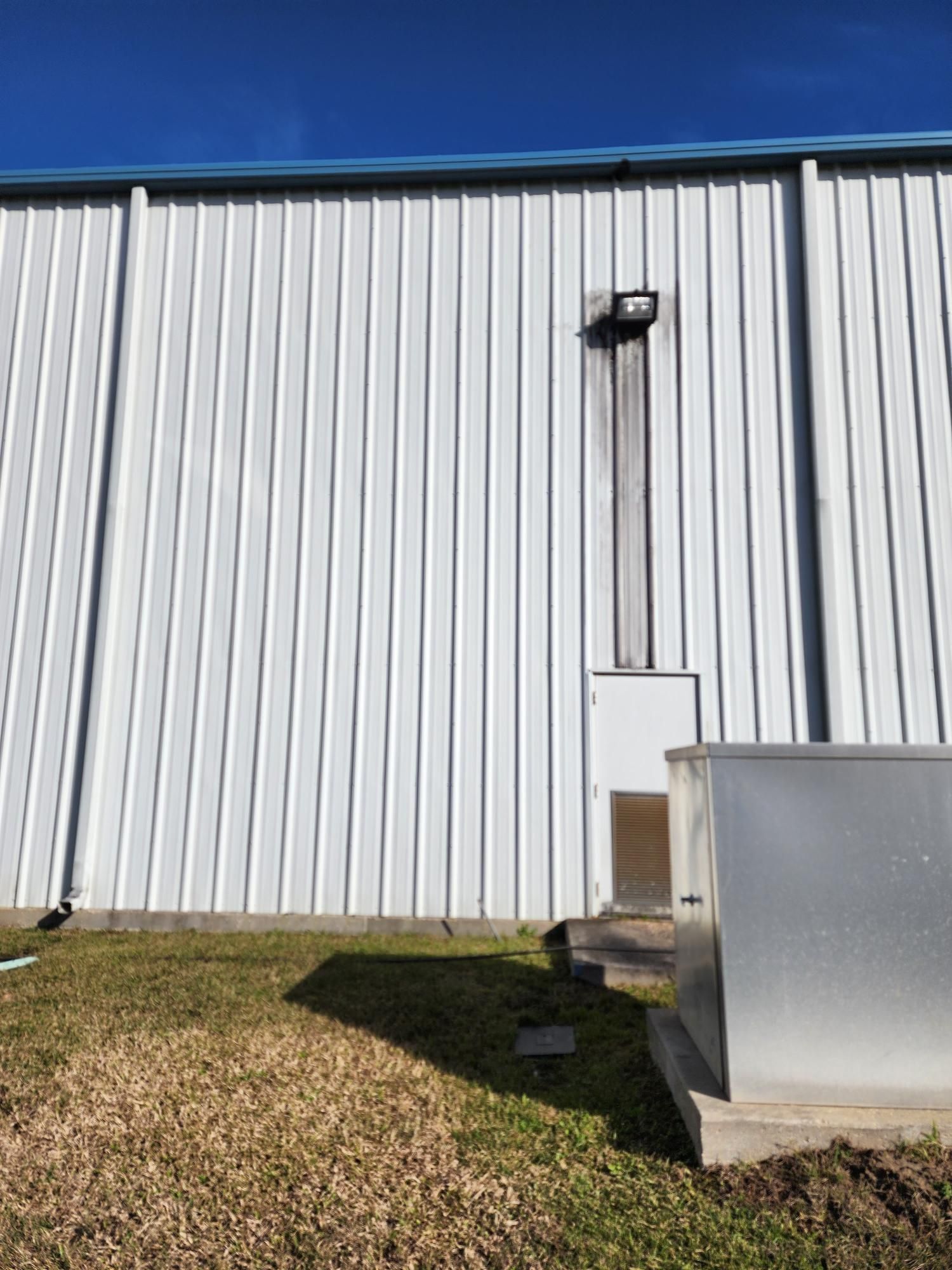 A large white building with a blue roof is sitting on top of a lush green field.