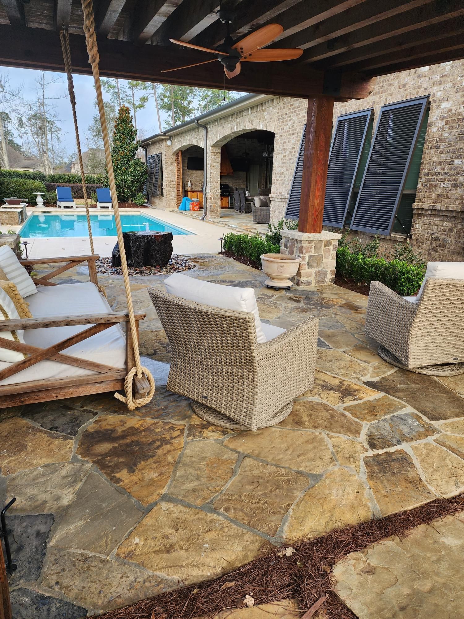 A patio with a swing , chairs , and a pool.