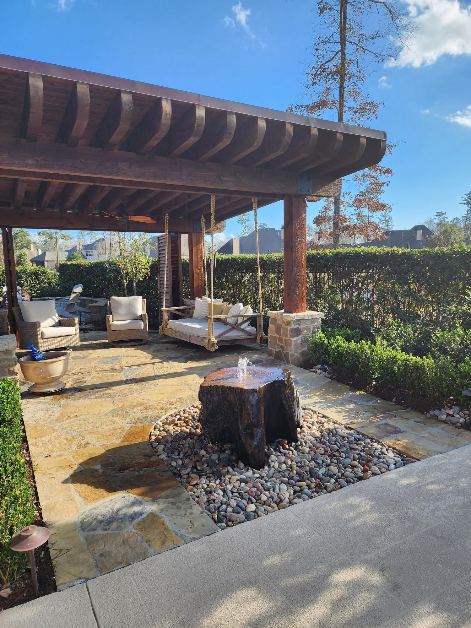 A patio with a pergola and a swing underneath it.
