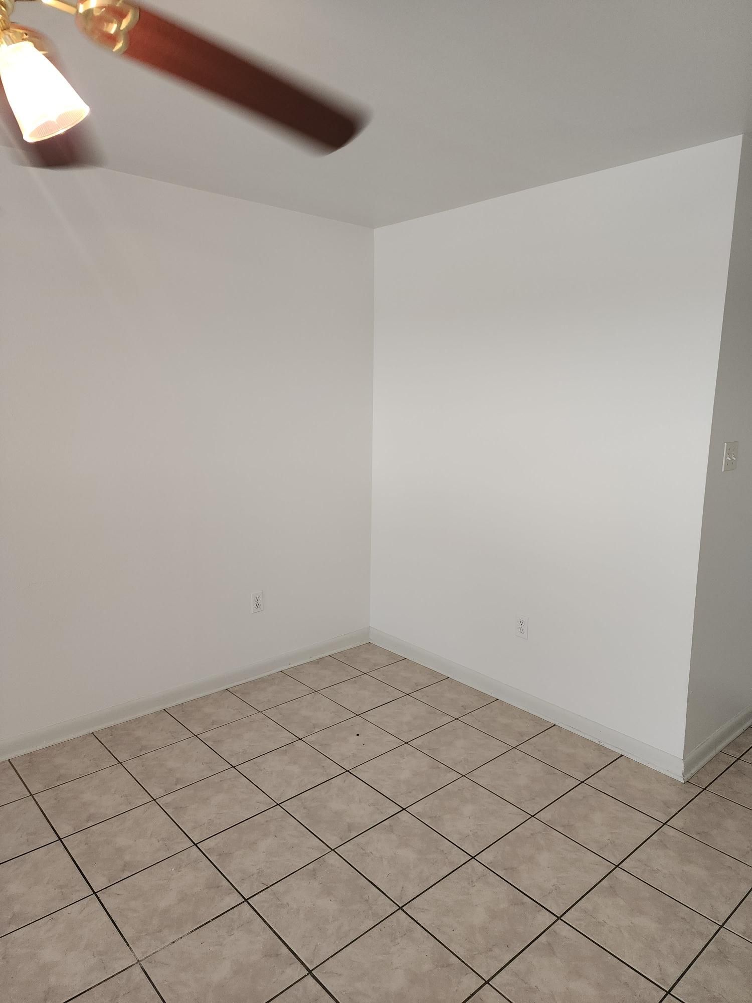 An empty room with a tiled floor and a ceiling fan.