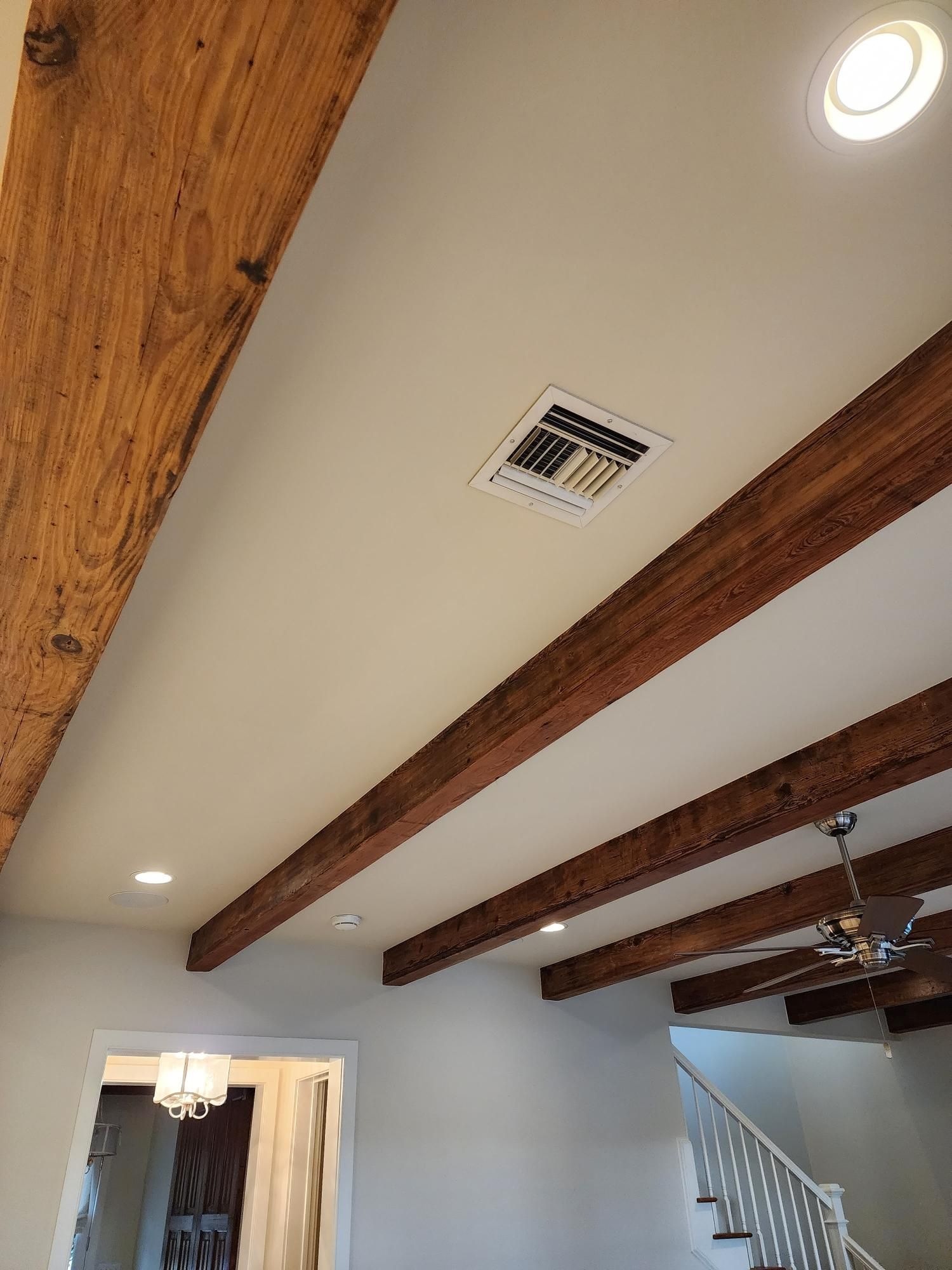 A living room with wooden beams and a ceiling fan.
