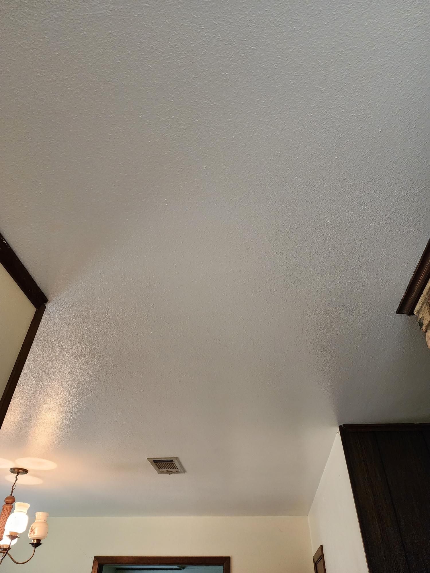 A white ceiling with a chandelier hanging from it in a room.