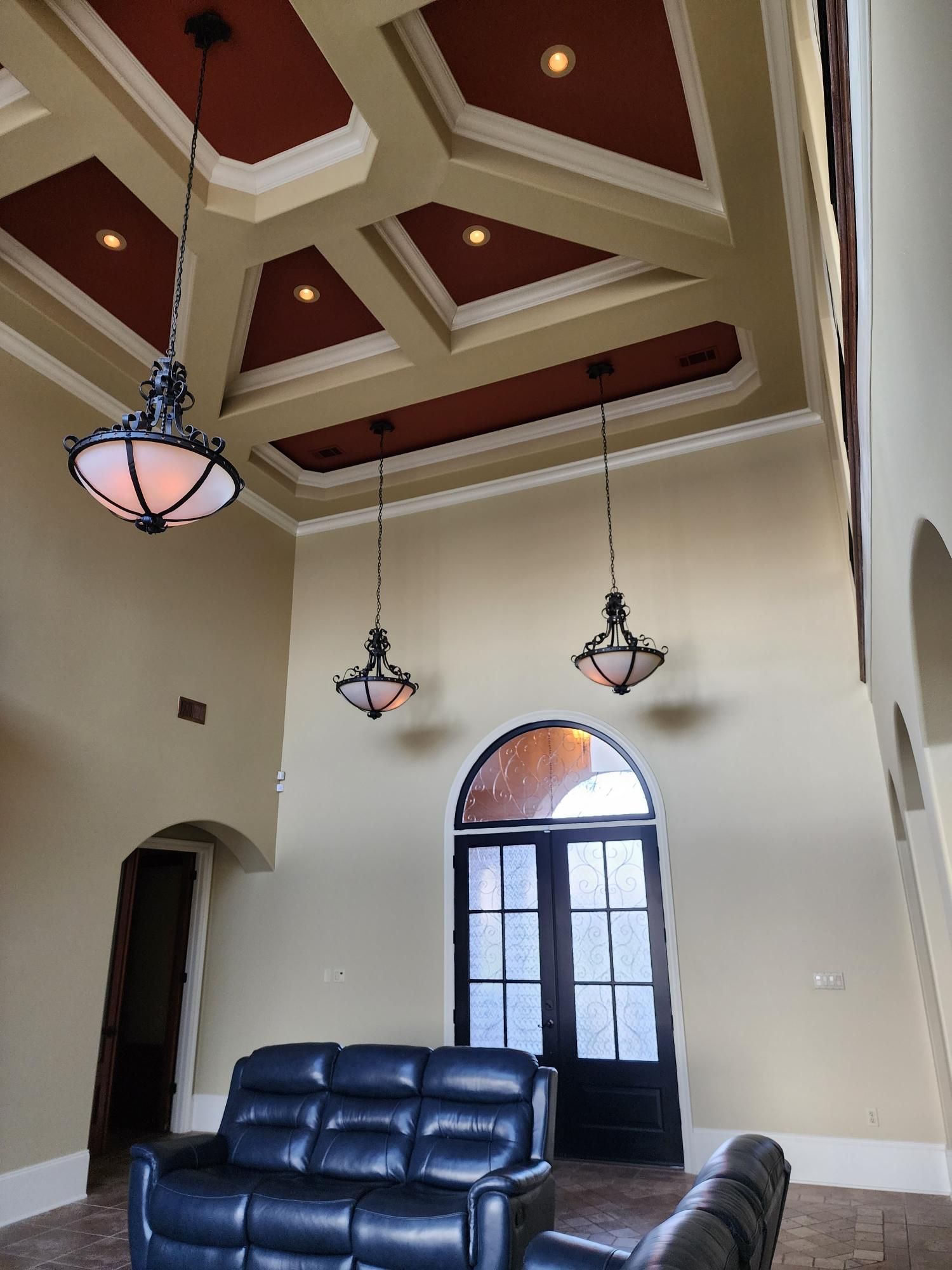 A living room with a couch and two chandeliers hanging from the ceiling