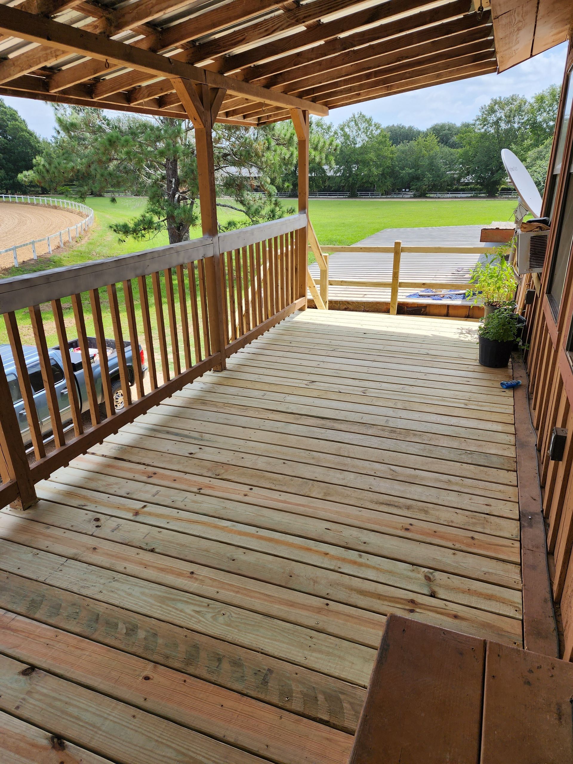 A wooden deck with a railing and a view of a field.