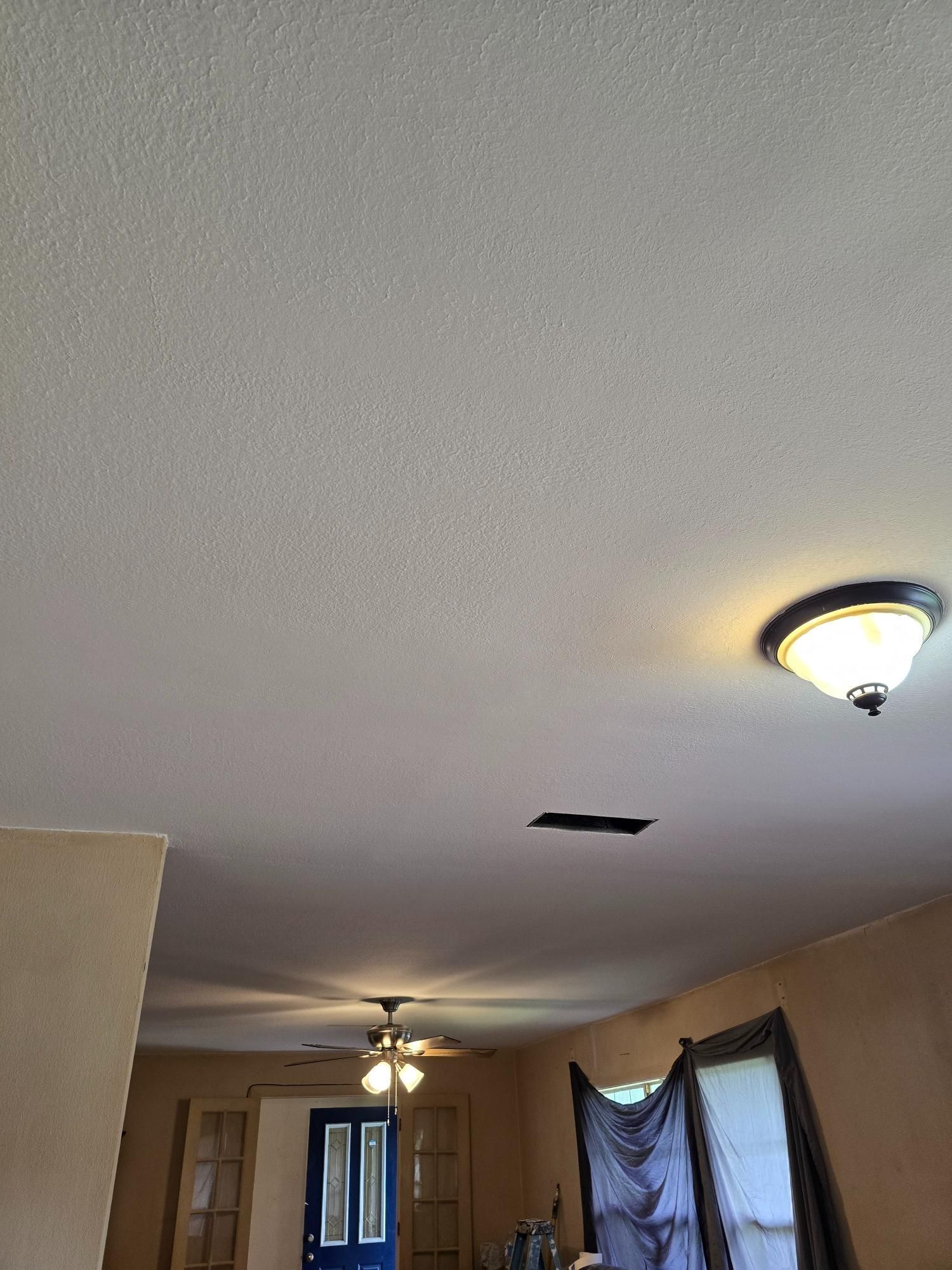 A living room with a ceiling fan and a light fixture.