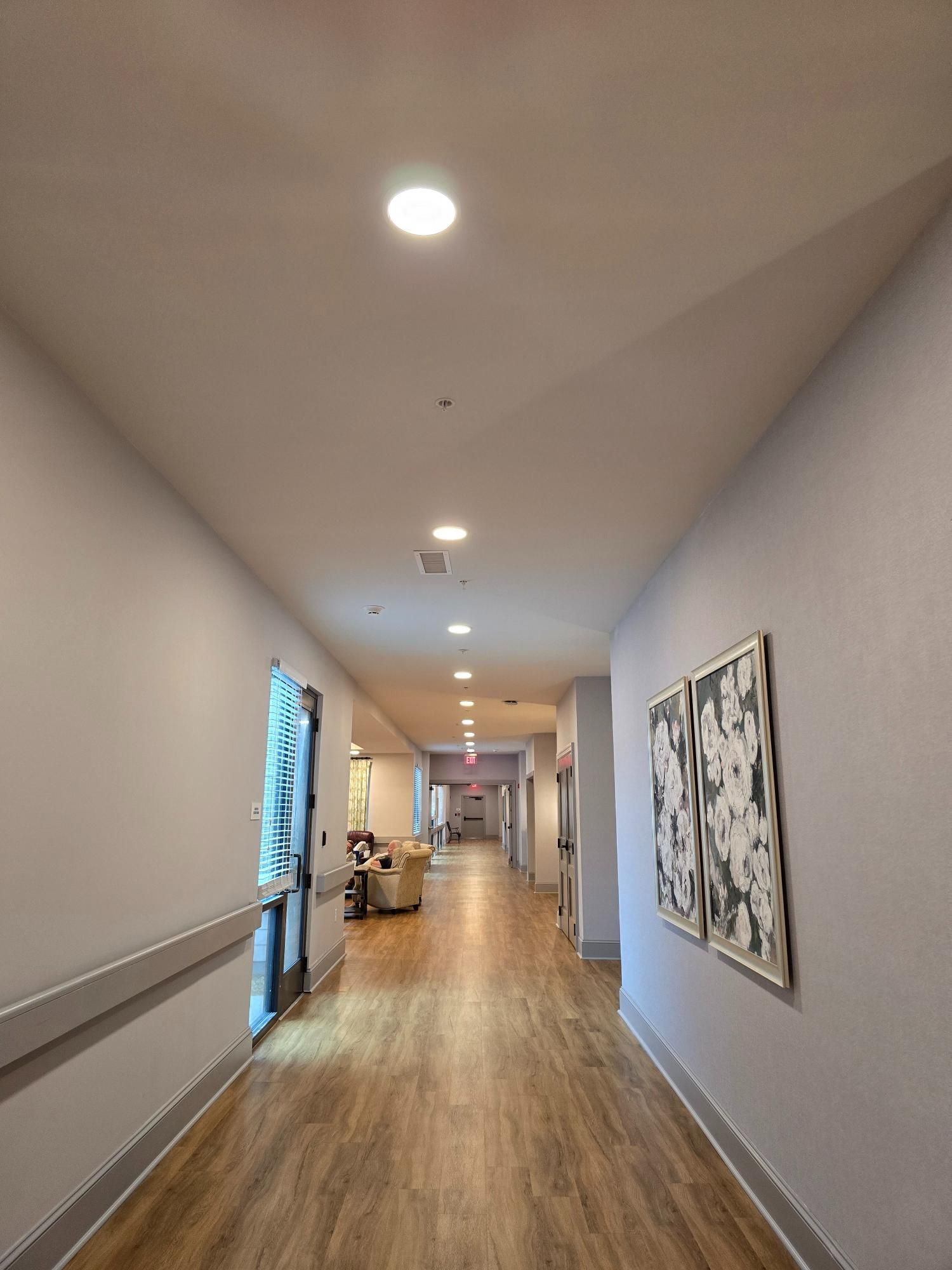 A long hallway with wooden floors and a painting on the wall.