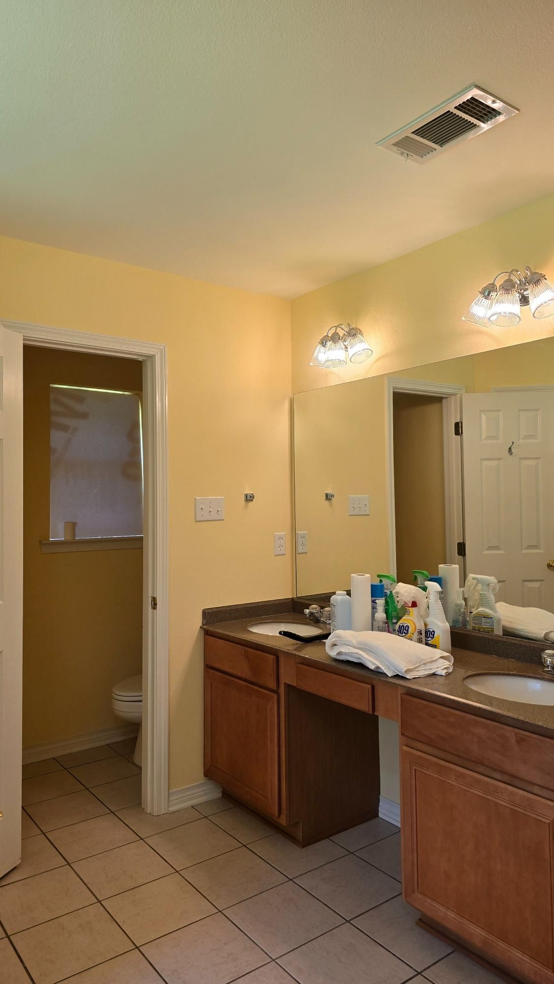 A bathroom with two sinks , a toilet and a mirror.