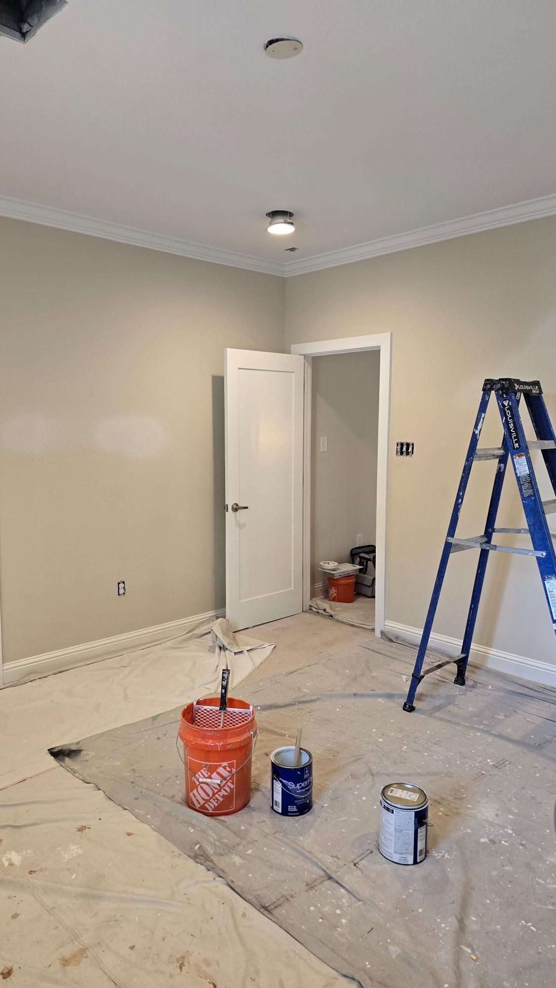 A room is being painted with buckets of paint and a ladder.