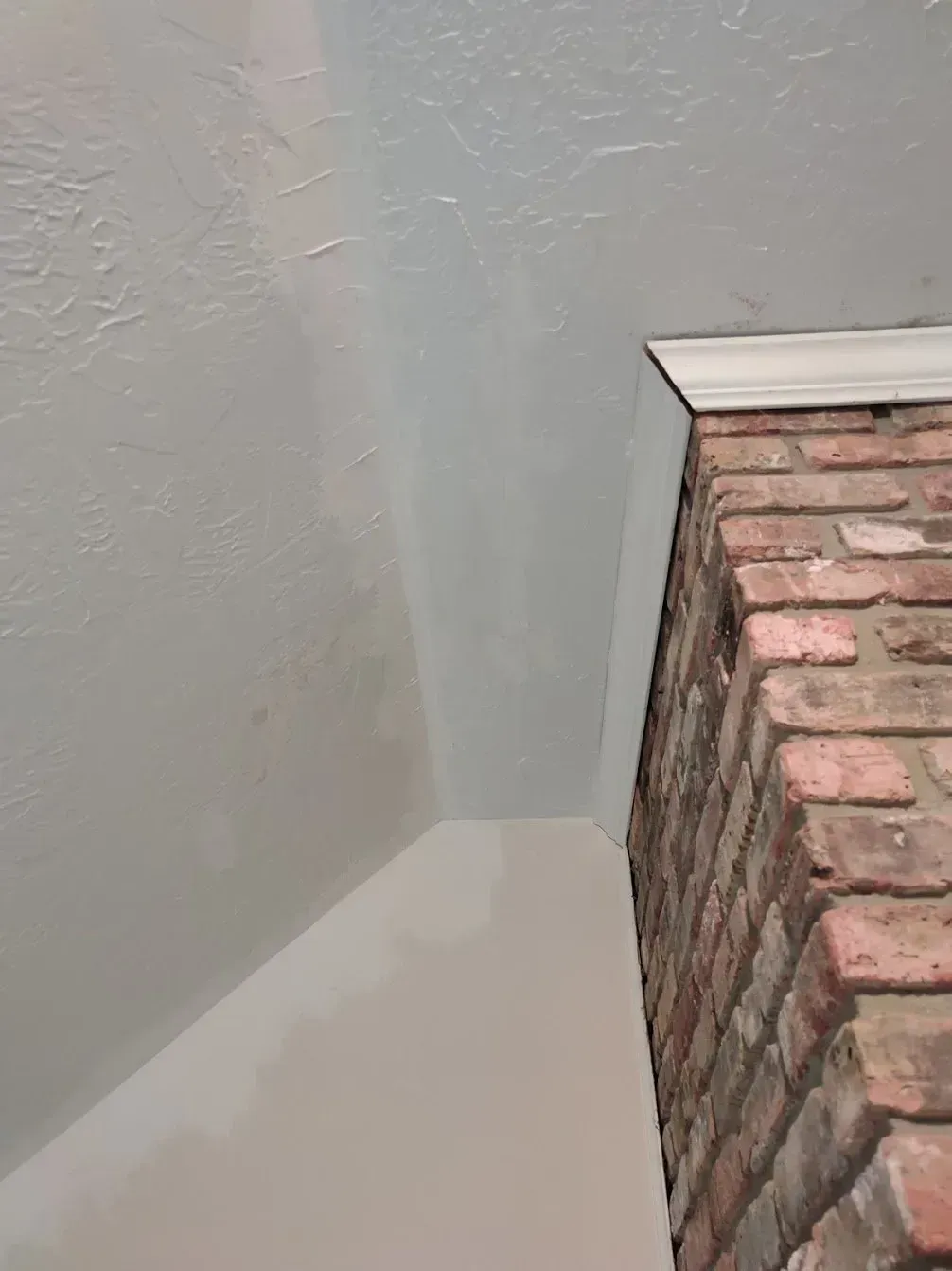 There is a brick fireplace in the corner of the room.